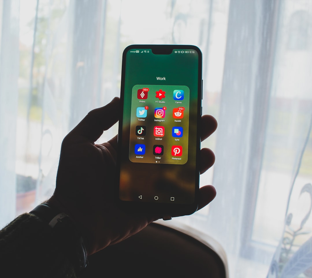 a person holding up a smart phone in front of a window