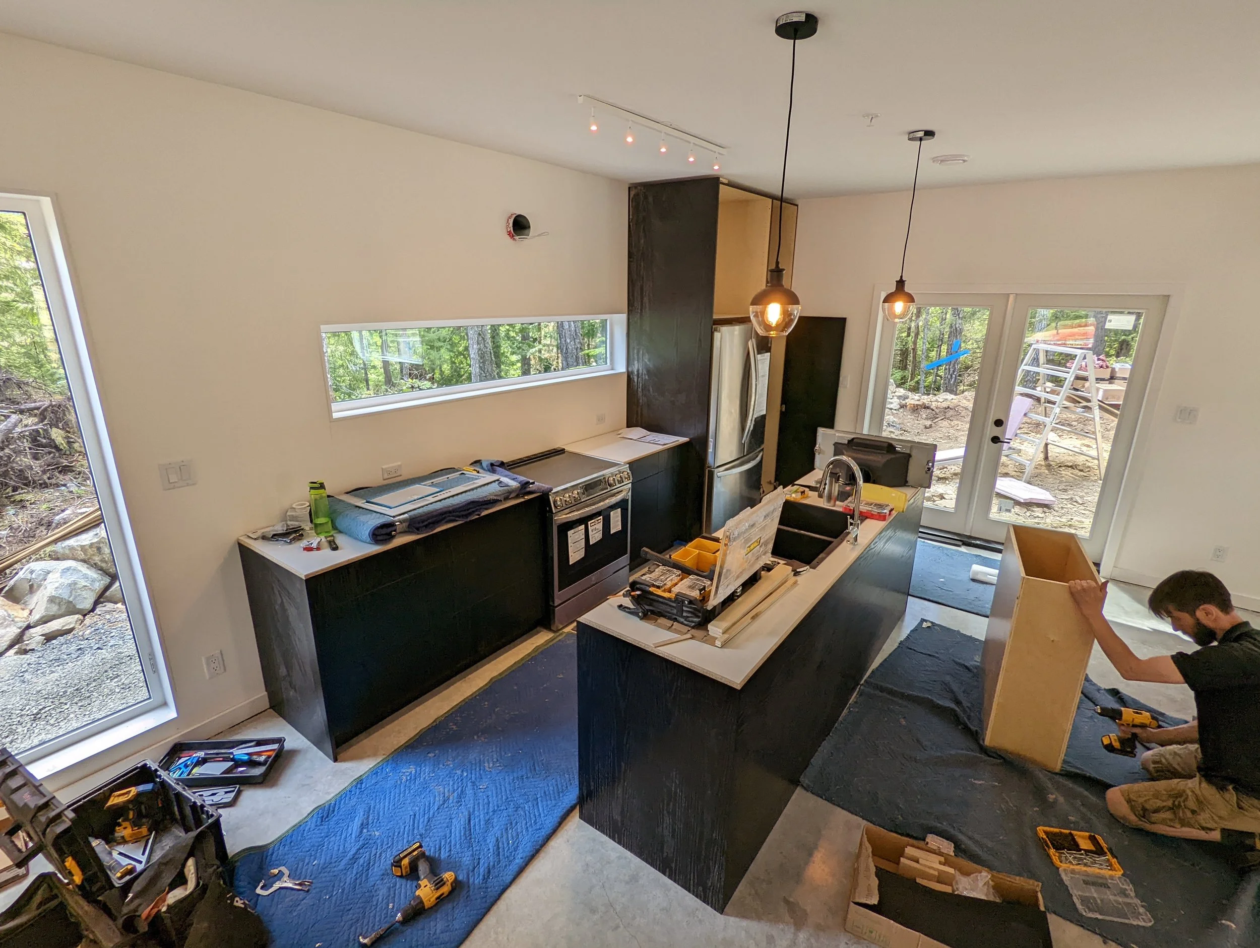 Modern two-story home with large glass windows, warmly lit interiors, and a balcony. Surrounded by trees and a manicured lawn at dusk. Cozy ambiance.