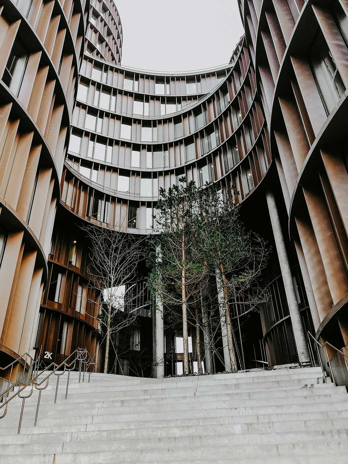 A modern building with a curved facade and trees growing in the courtyard