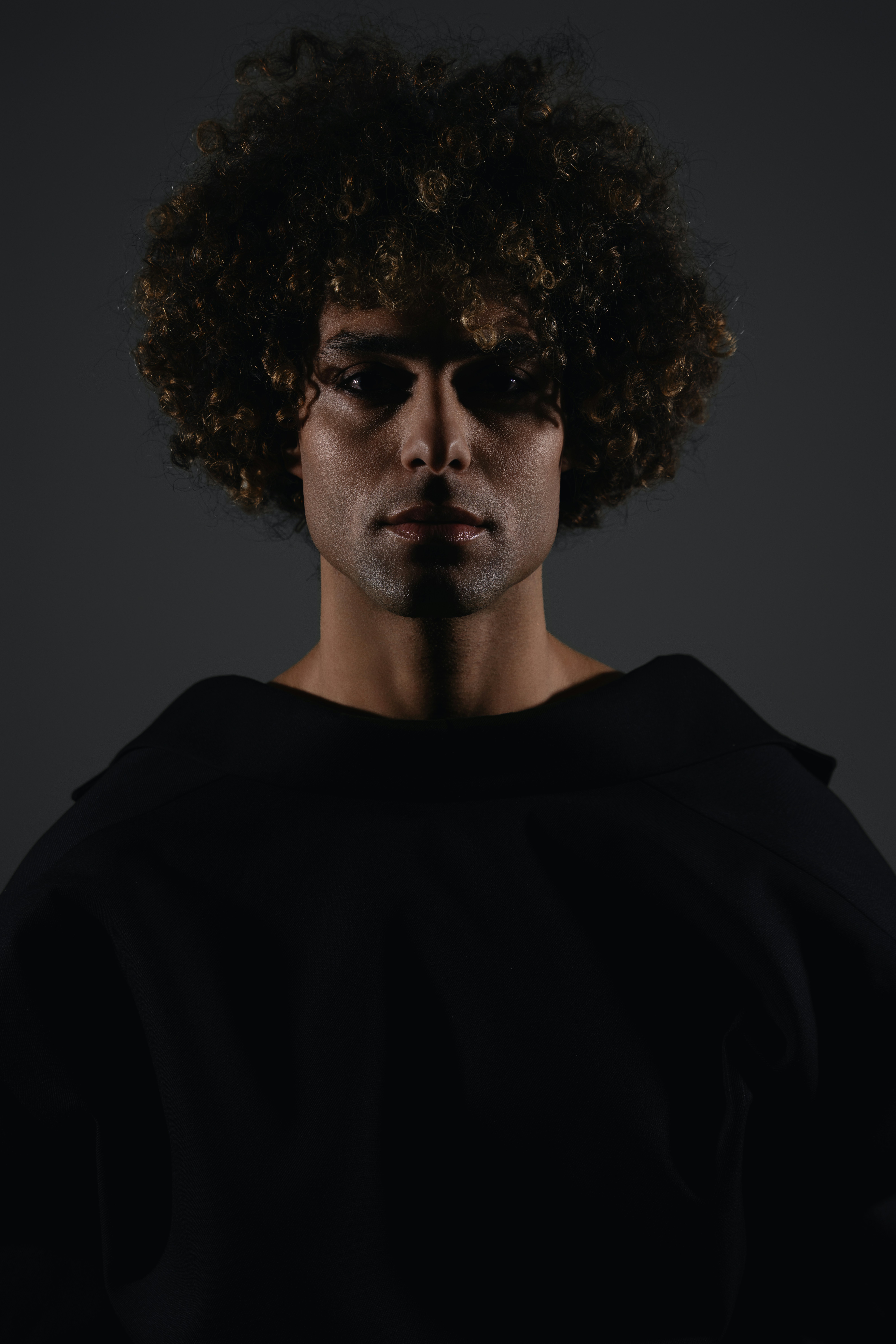 A man with an afro standing in a dark room