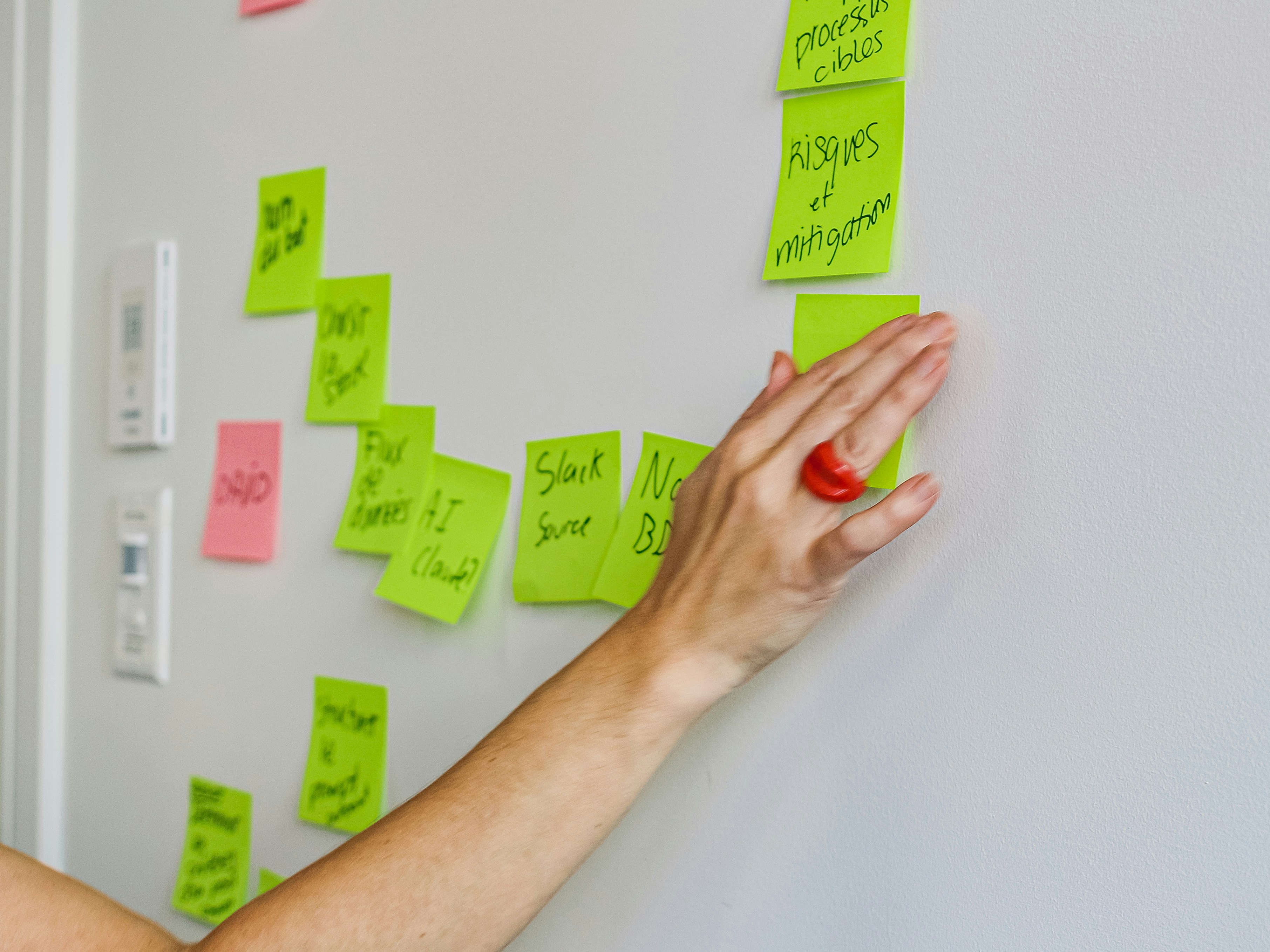 Hand placing a sticky note on a wall.