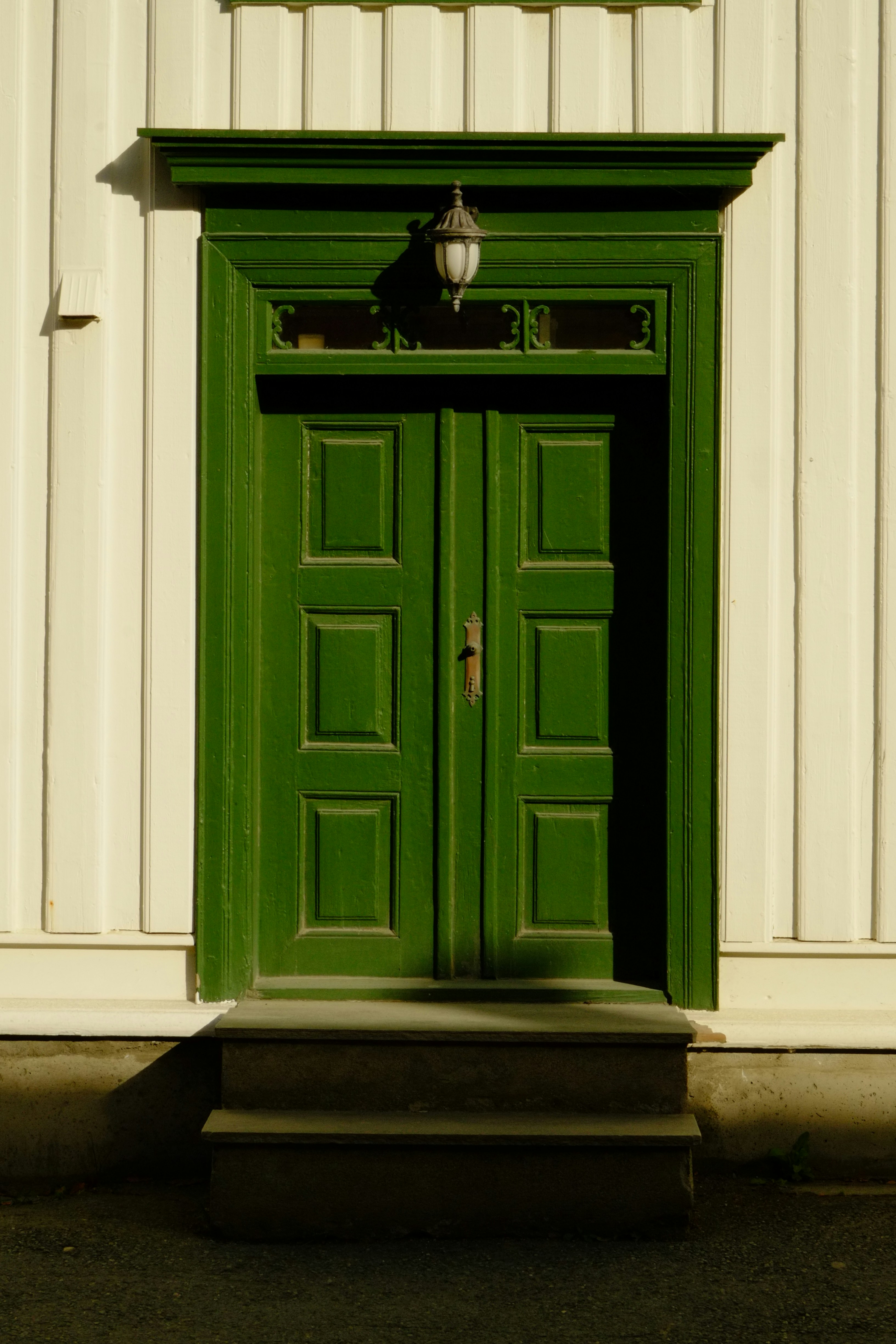 A closed green double door with steps