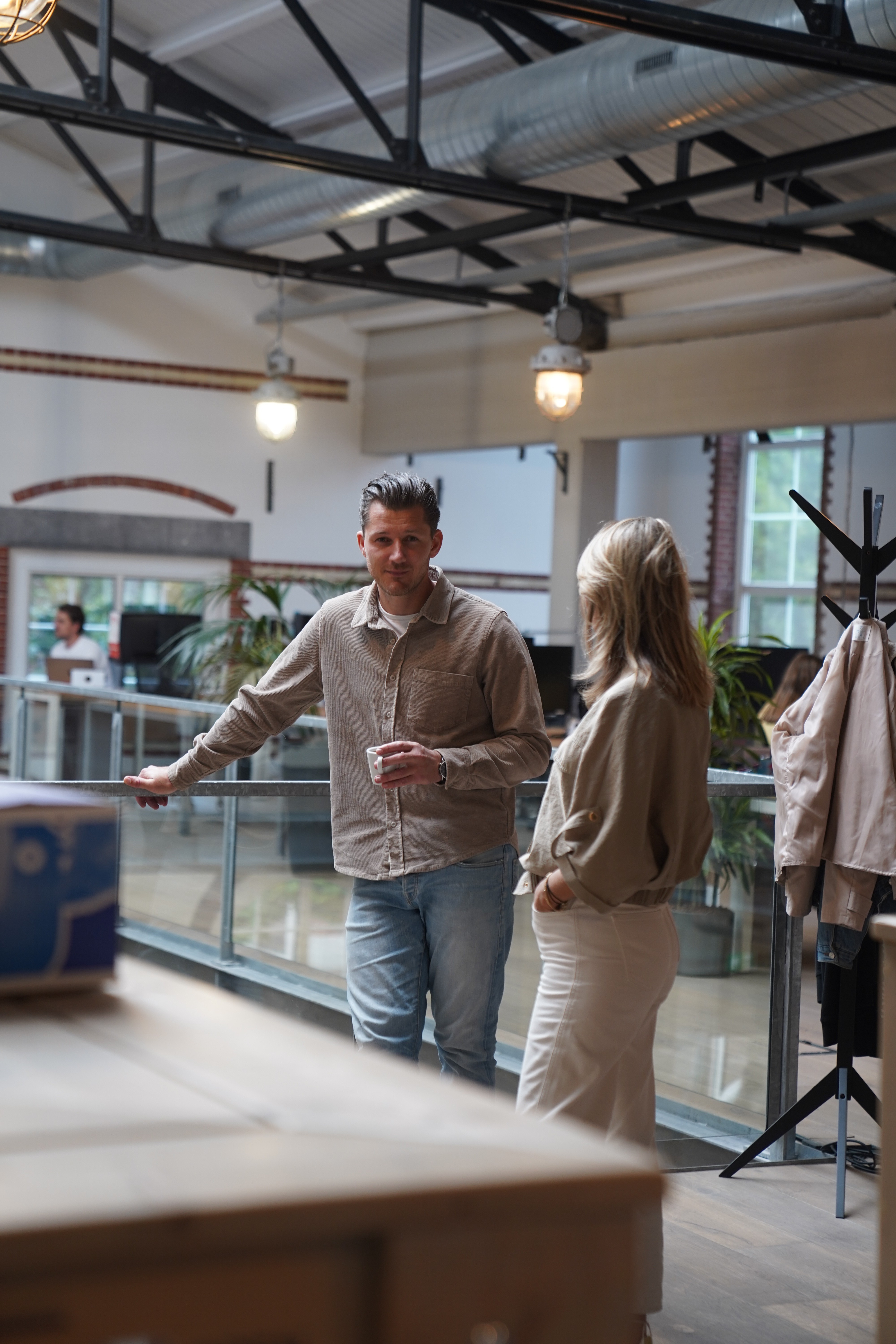 a man smirking at the photographer while holding a cup of coffee