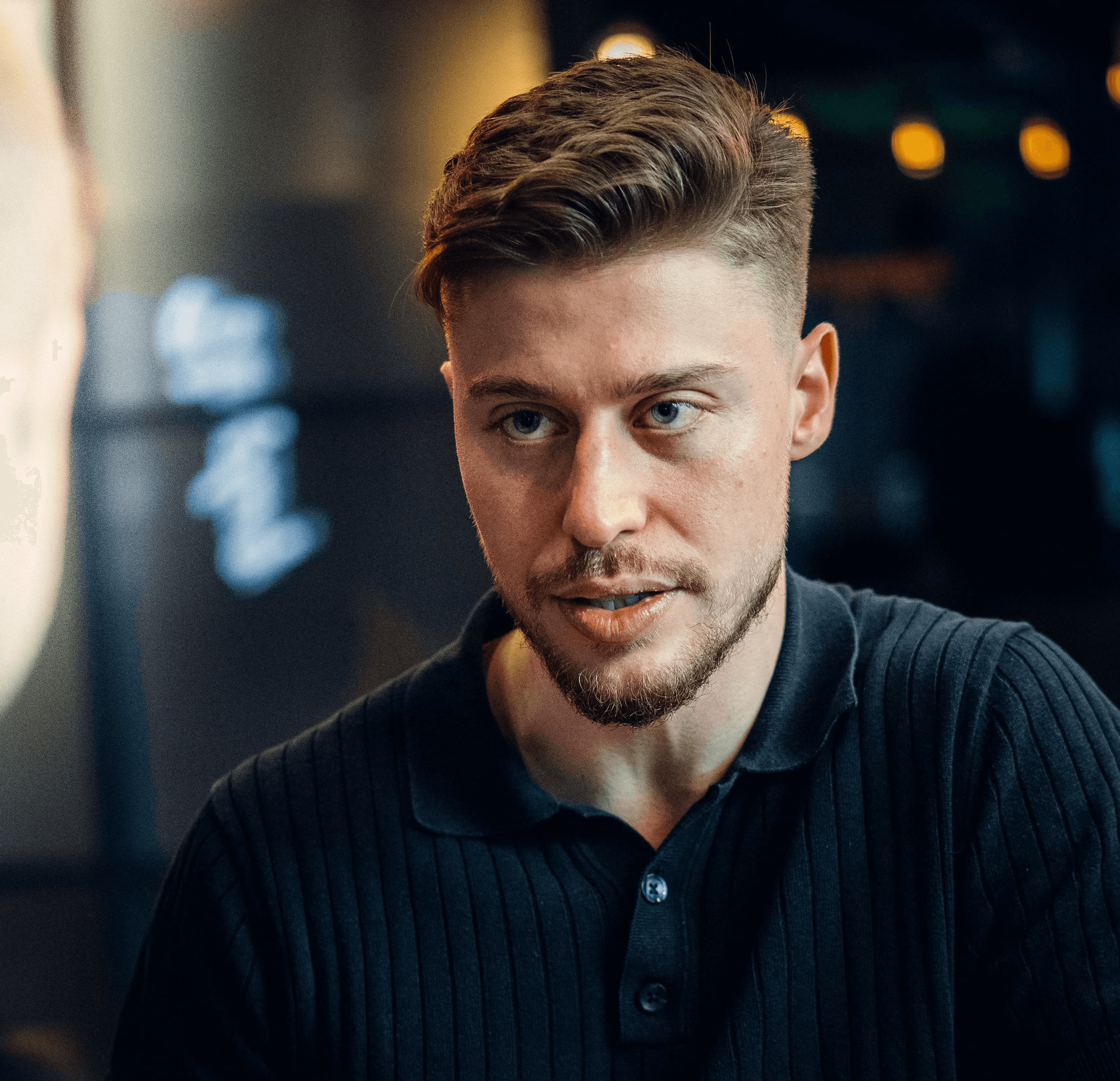 Junger Mann im Gespräch. Portrait mit Bart und modischer Frisur.