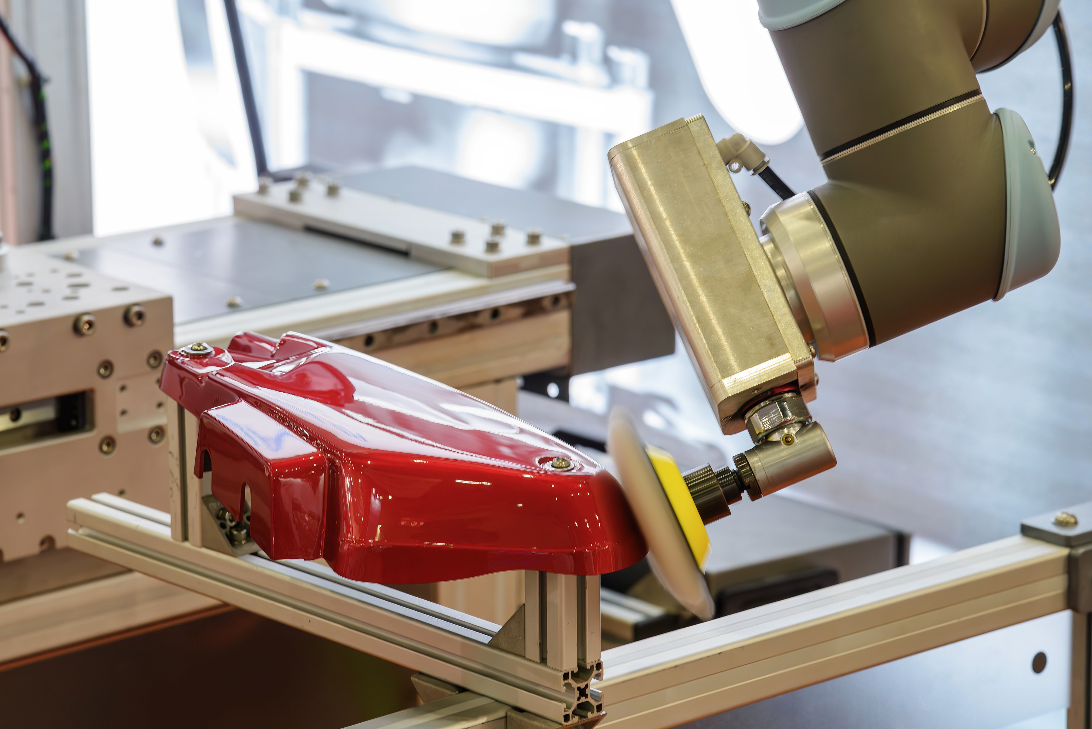 A close-up of a red clamp securing materials on a workbench, with tools and wood nearby in a workshop setting.