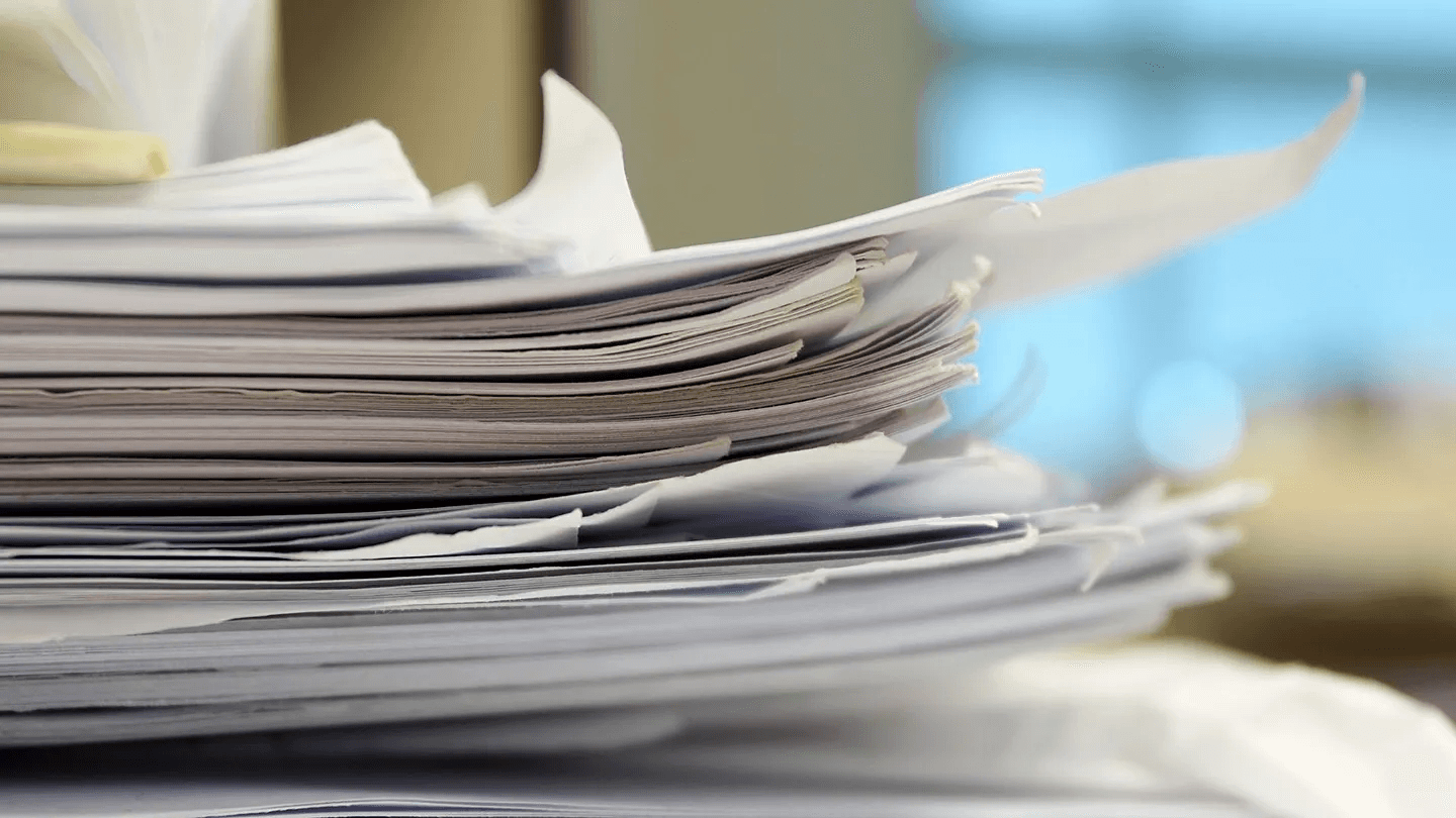 High school student comparing research publication certificates and academic papers on a desk, evaluating college application value