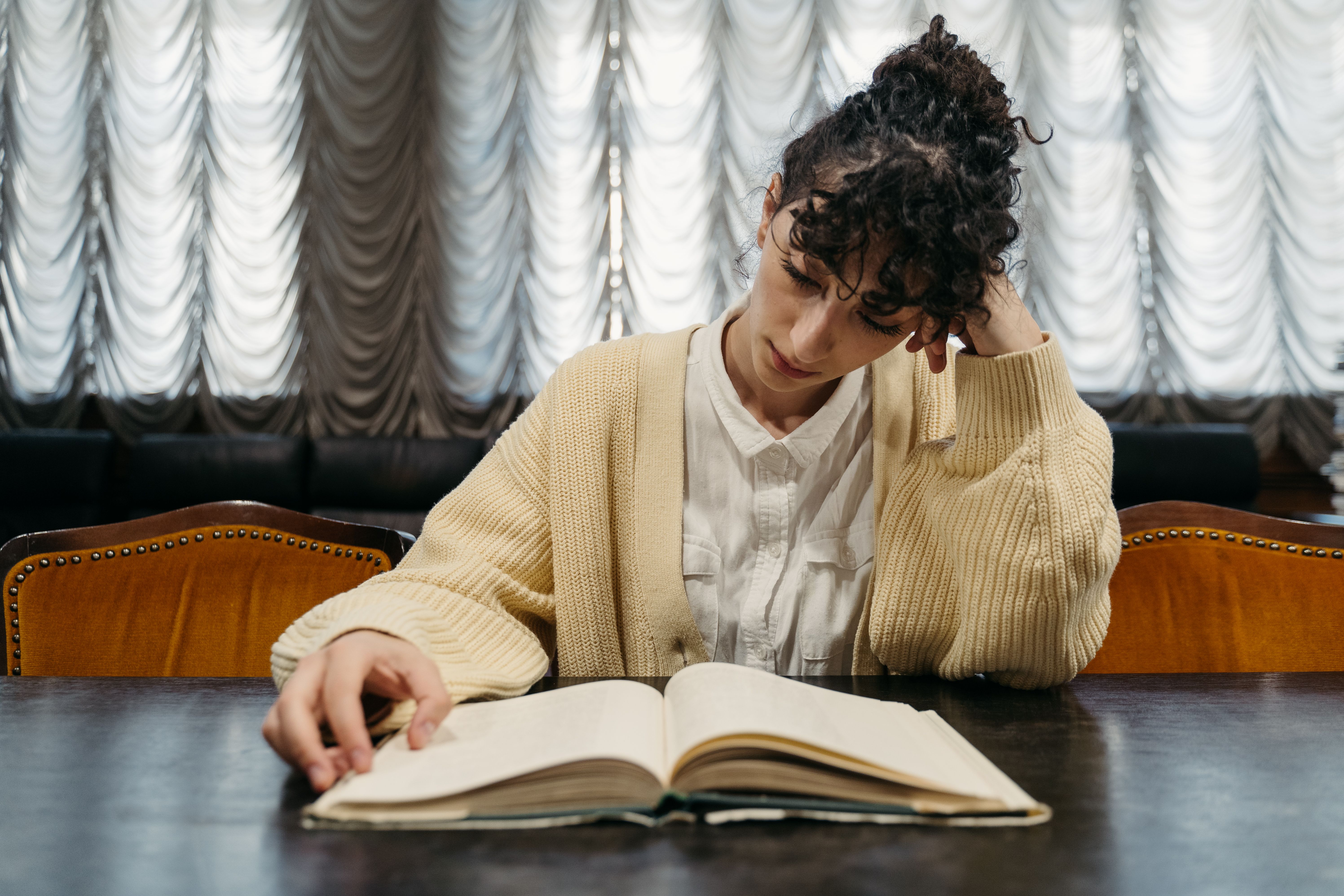 a-woman-deeply-engaged-in-reading-a-book-at-a-table,-capturing-a-serene-learning - tima-miroshnichenko (pexels)