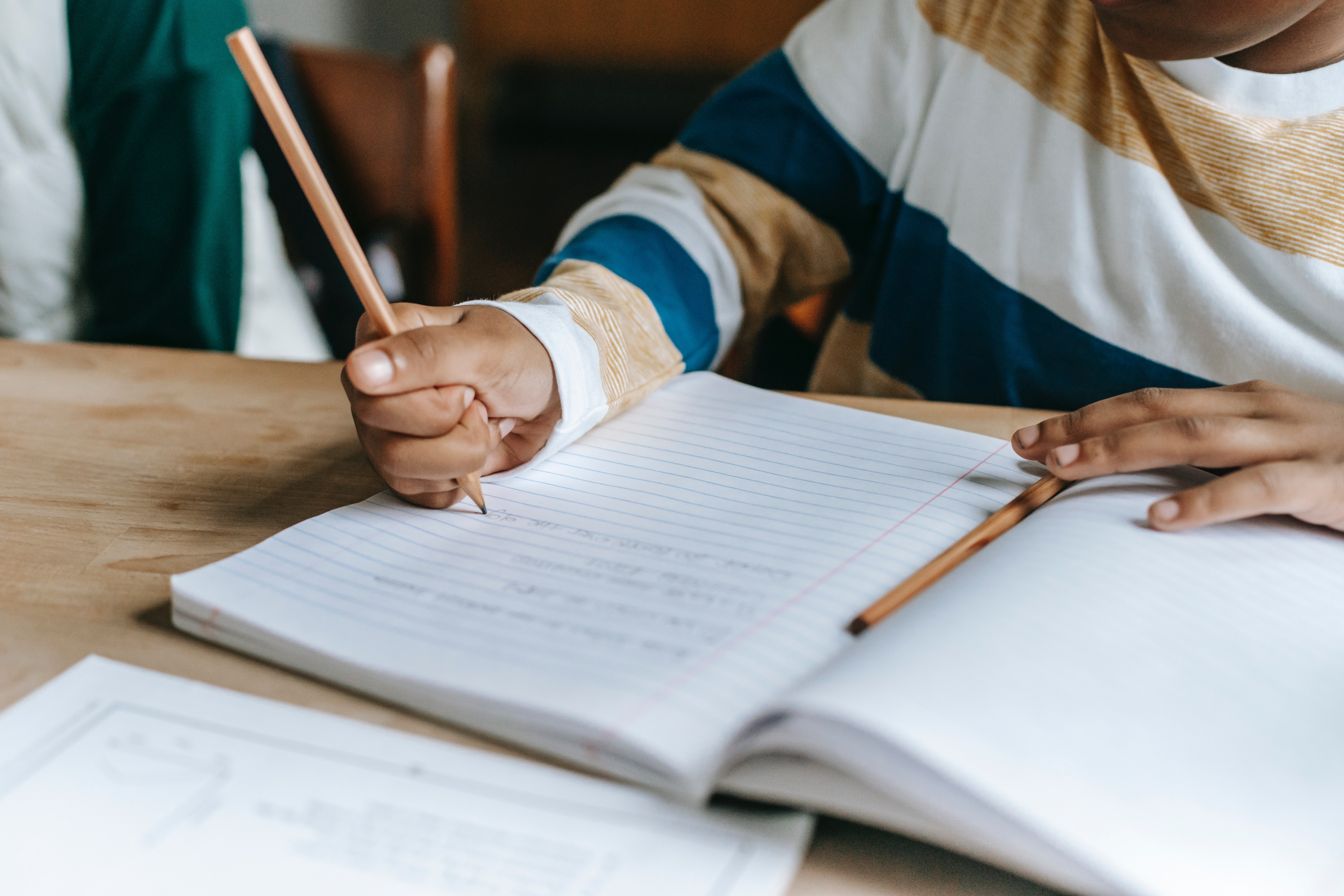 Student writing in book image