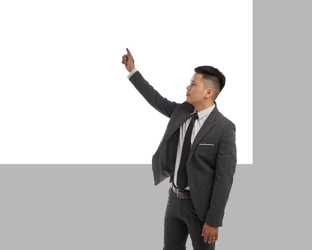 business professional pointing at a digital dashboard on a wall-mounted screen showing line graphs and charts, team members listening, modern conference room