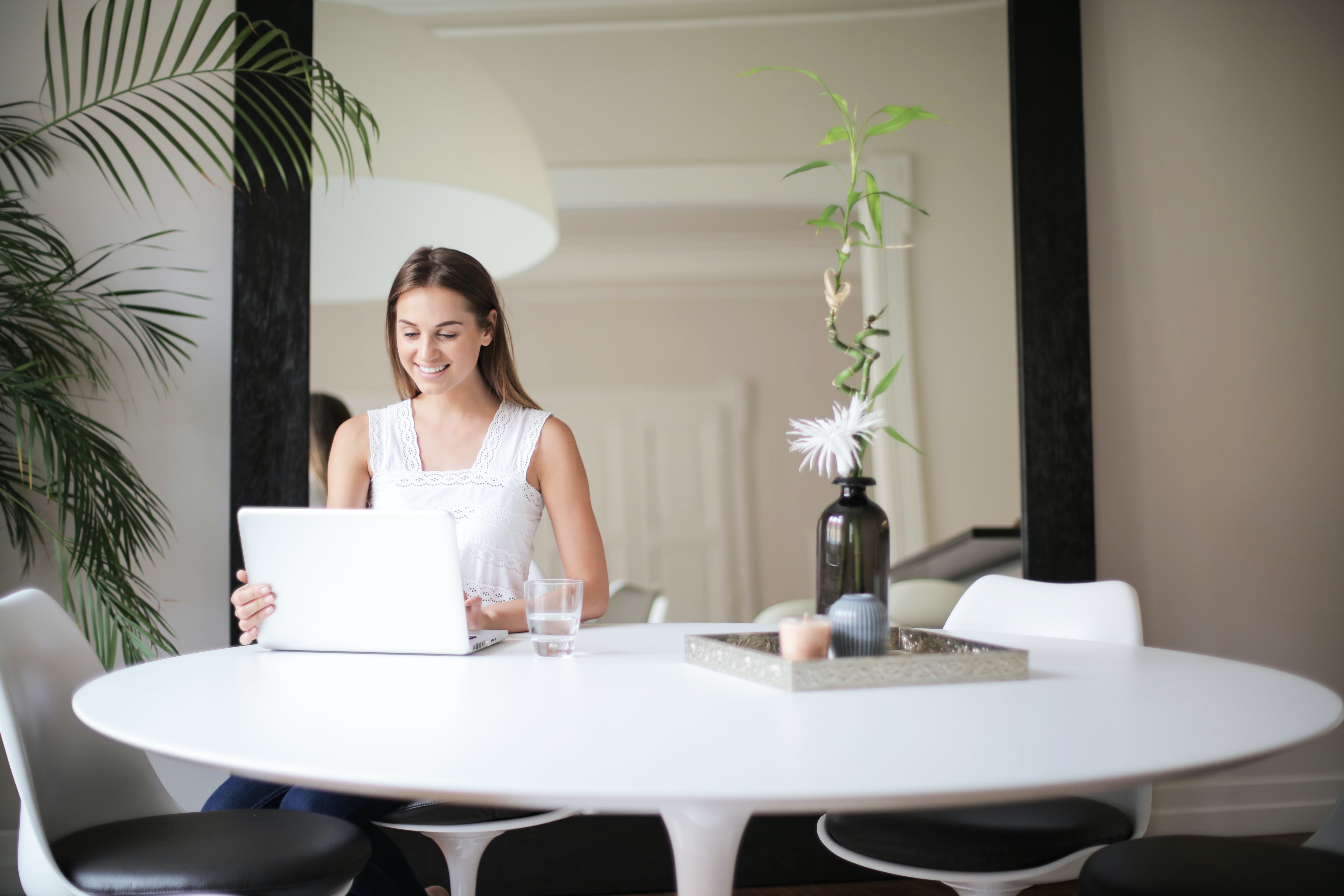 Woman in white sleeveles mastering cold emails in front of table with macbook