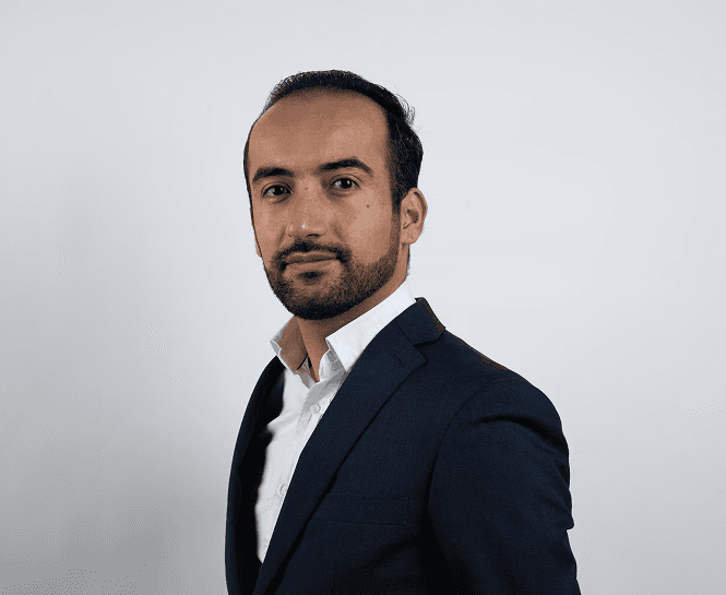 Foto van Niwar, eigenaar van vsocheque.nl. Man in pak die de camera in kijkt.