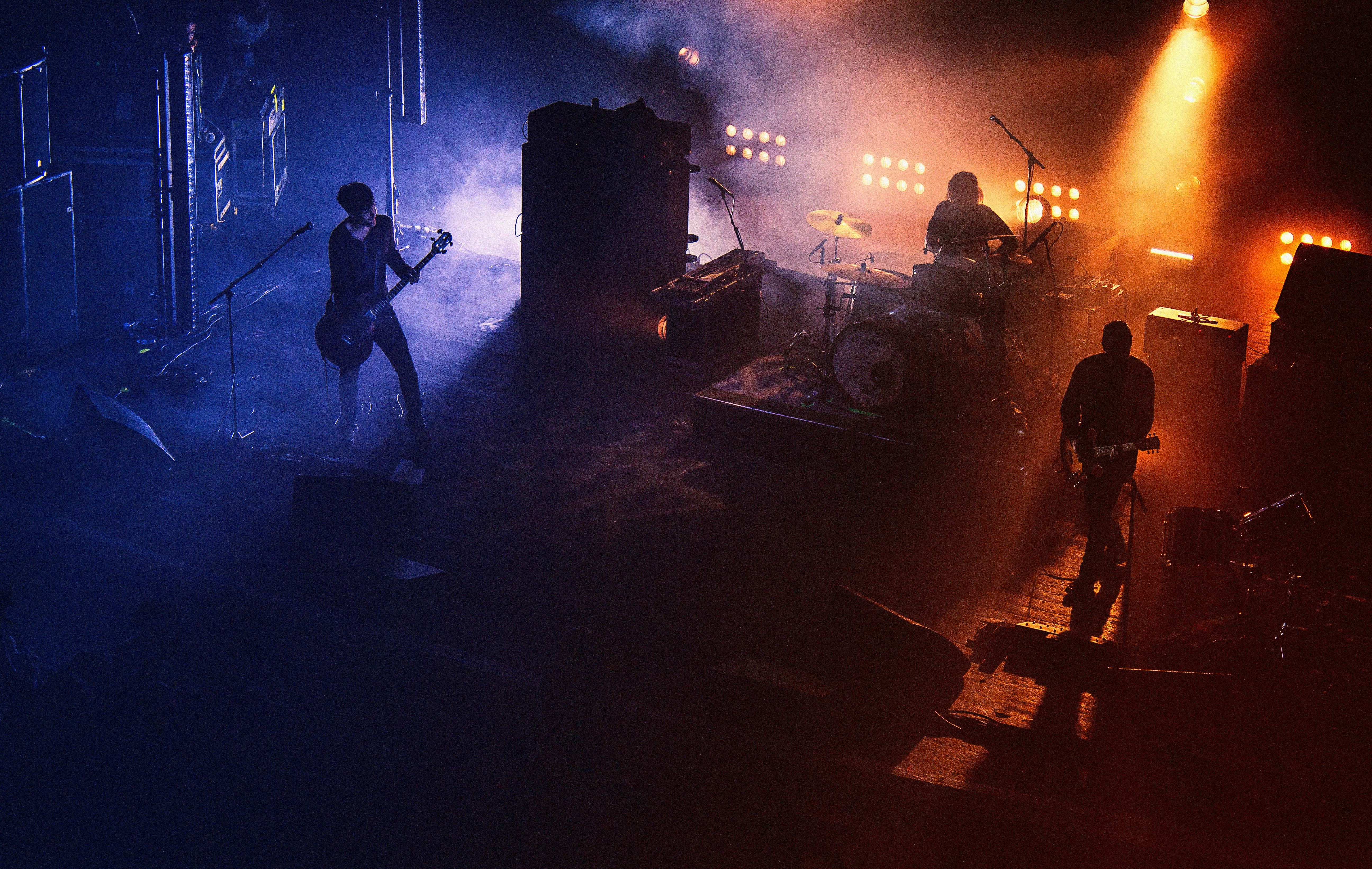 A red and blue light stage highlighting electric guitar players on either side