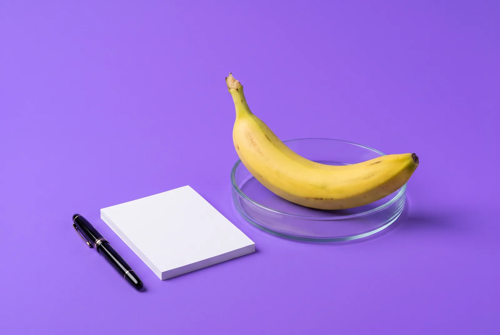 A banana in a petri dish beside blank papers and a fountain pen, asking whether death grip syndrome is real