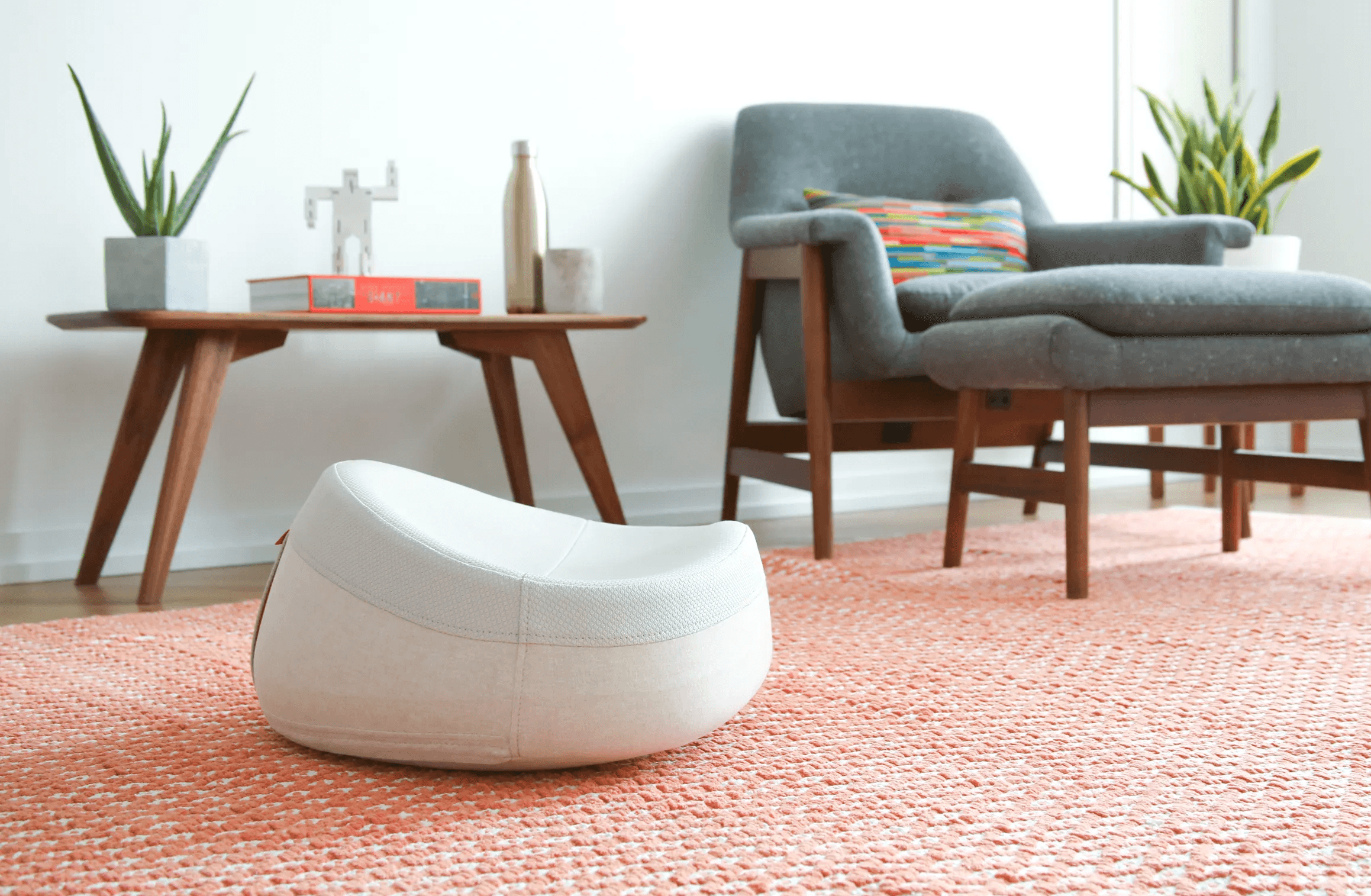 White UNDO meditation cushion in a modern living room with an orange rug