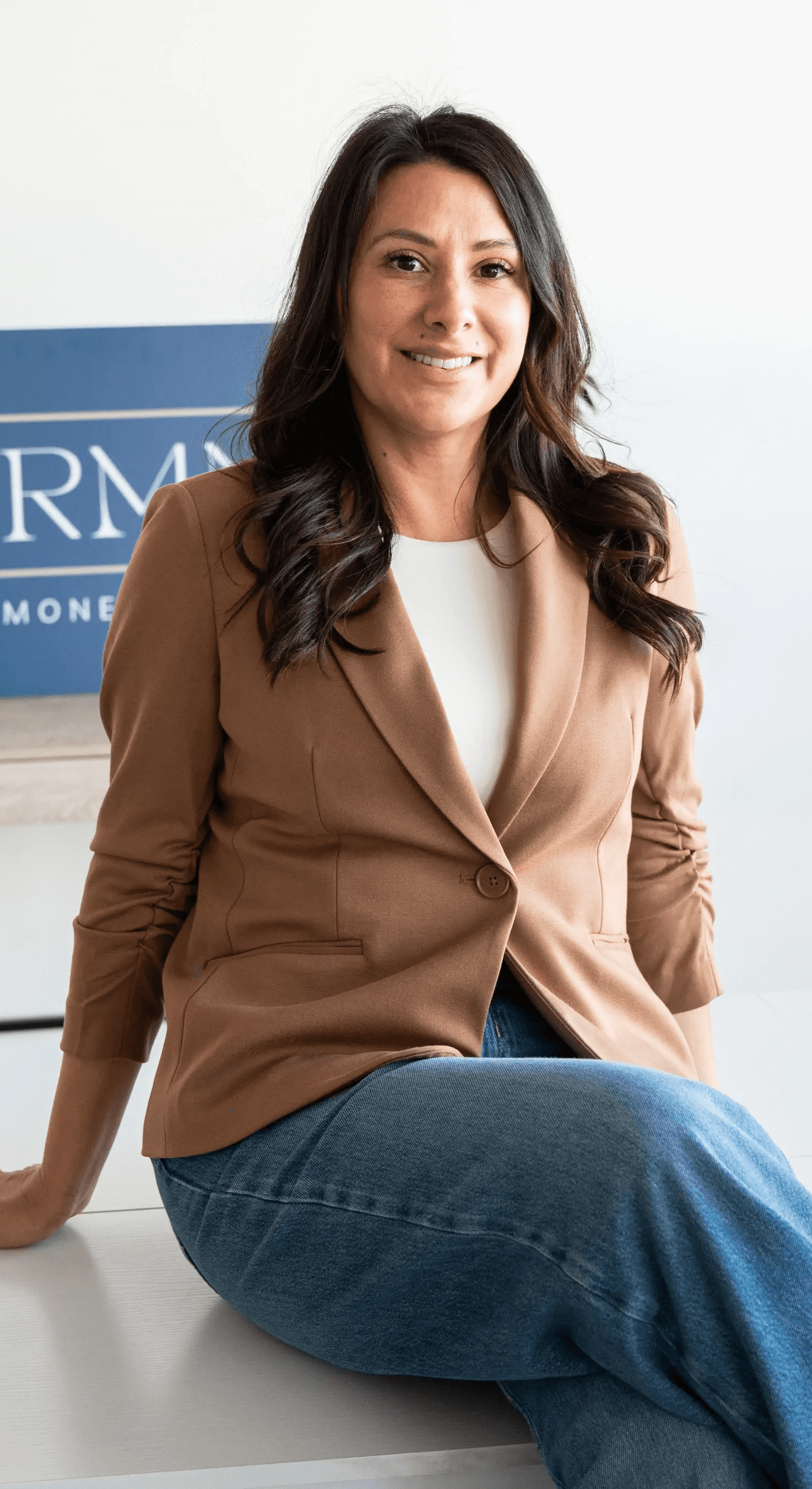 Portrait of Jamie Ruiz, a certified Physician Associate, smiling in a professional medical setting with shelves of supplements and medical products in the background.