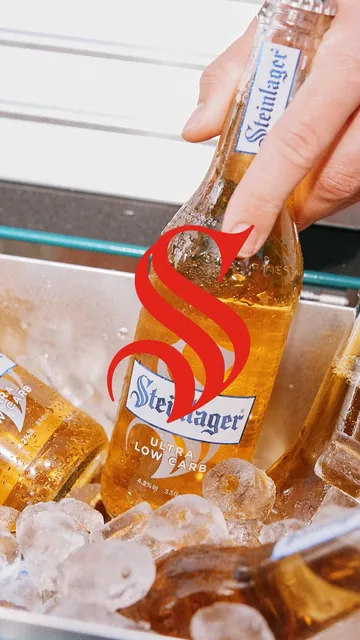 A hand lifts a Steinlager from an ice bucket