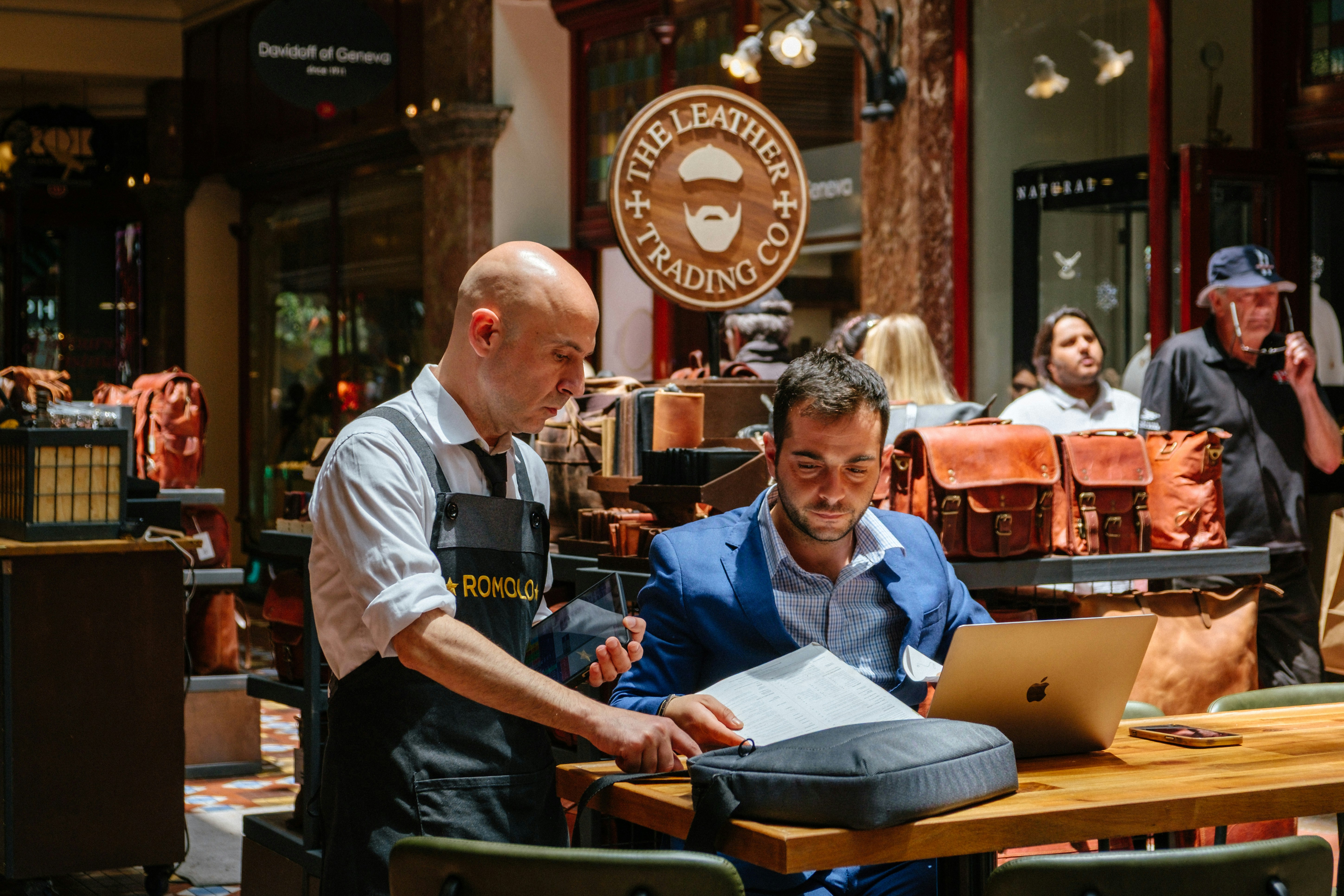 Two men looking at laptop and papers in store