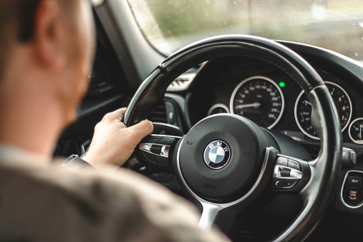 Driver holding a BMW steering wheel, illustrating the French driver's license exchange process