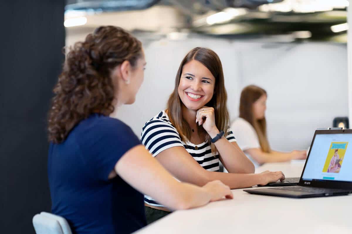 Two female Sovendus employees chatting at a table in the Sovendus office