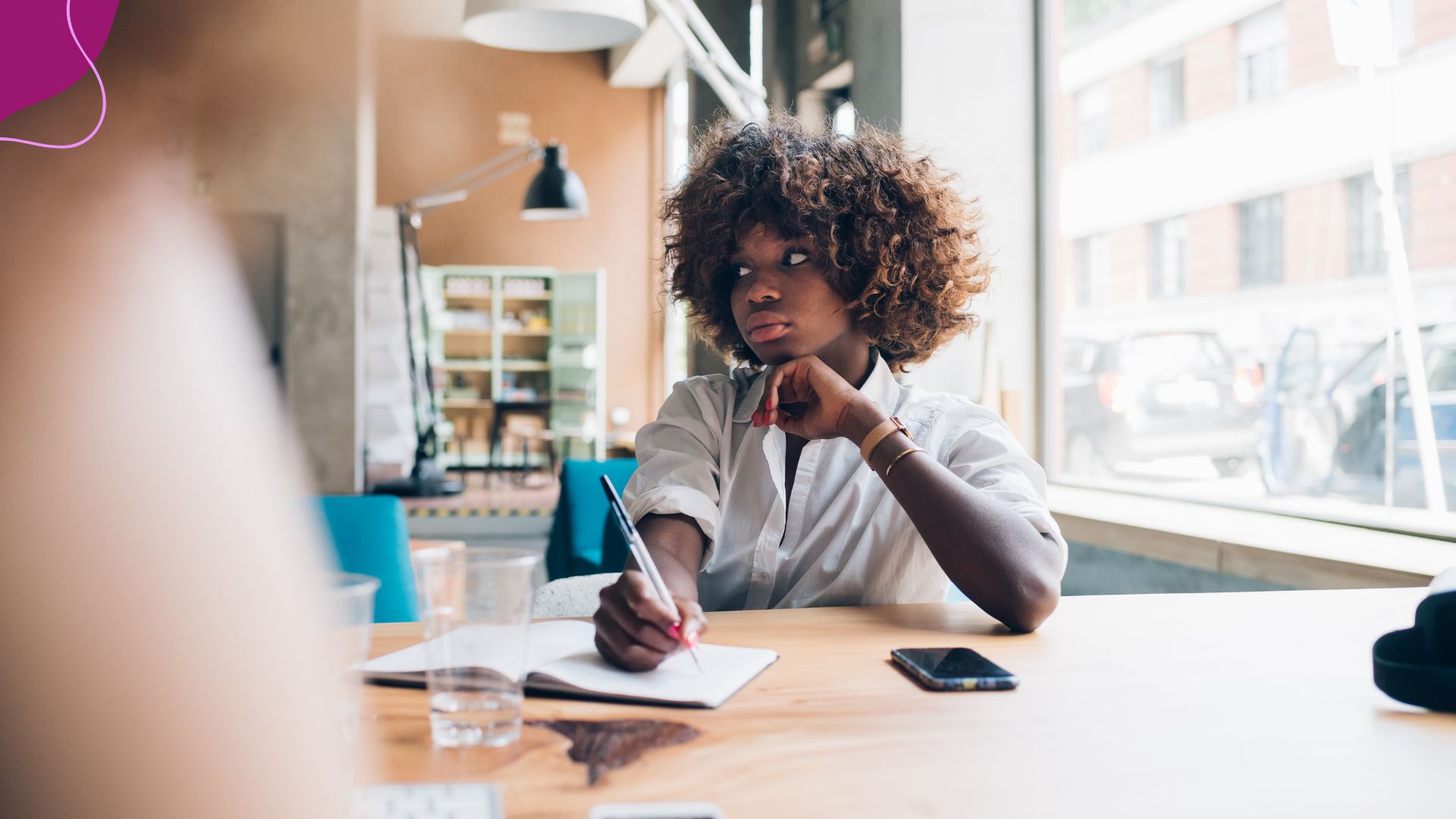 Woman sitting  at desk in office  with afro hair and chin resting on hand