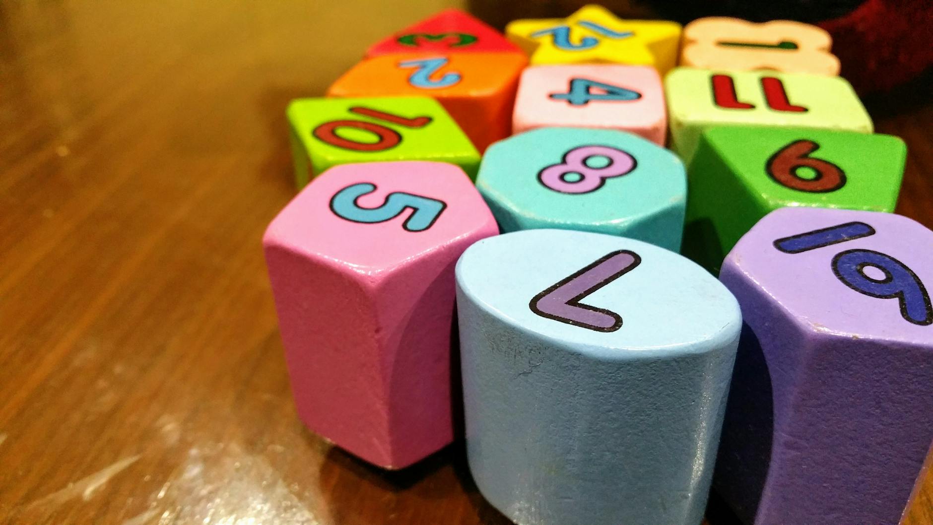 Close-up of colorful plastic math manipulatives and flashcards arranged on a wooden school table.
