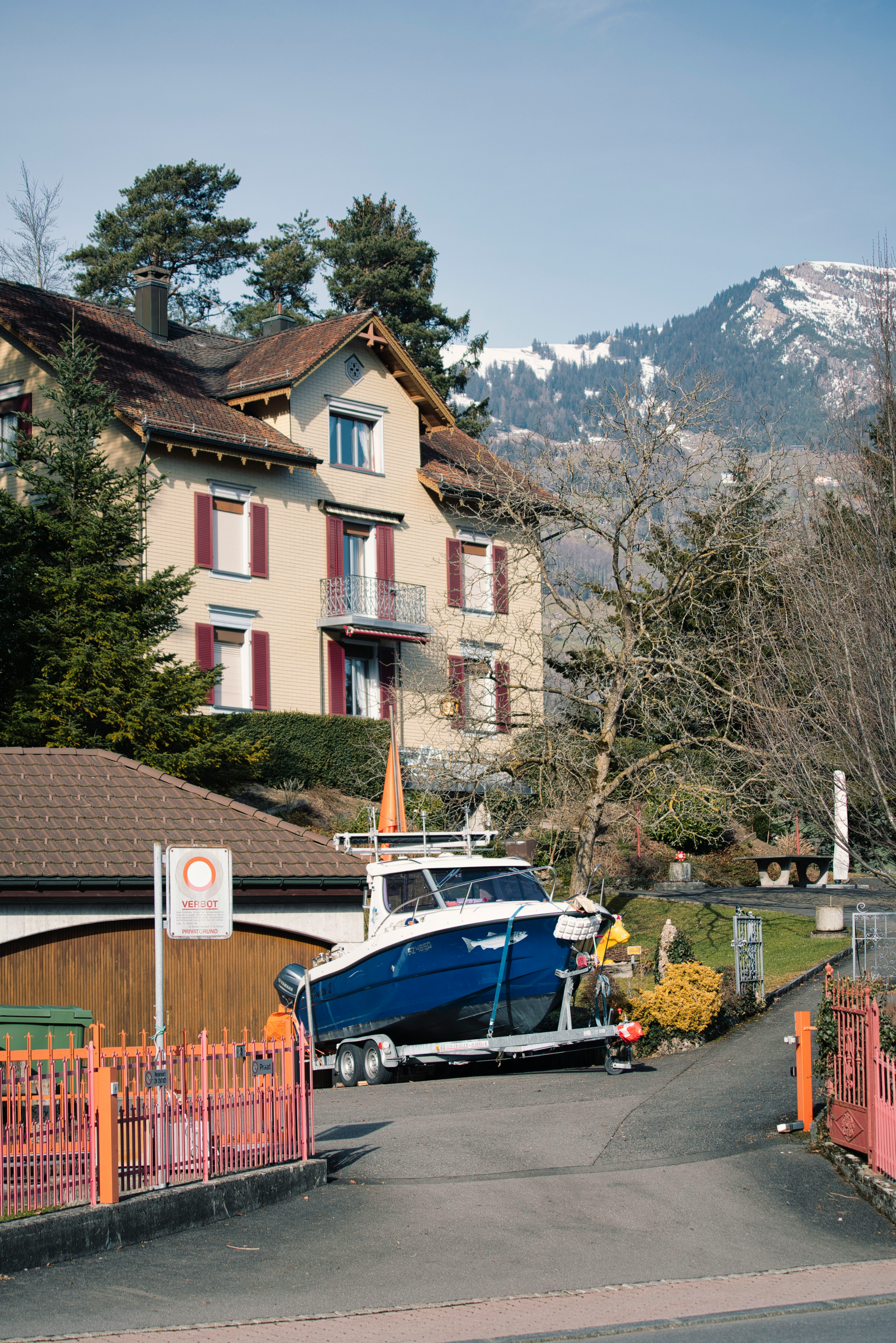 Residential Swiss house with mountain backdrop and boat on trailer in driveway symbolizes Housing in Switzerland