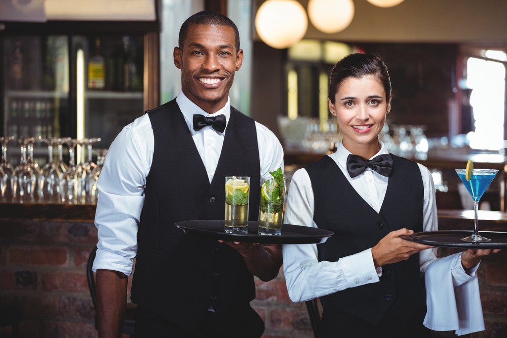 Waiter and waitress holding a serving tray.