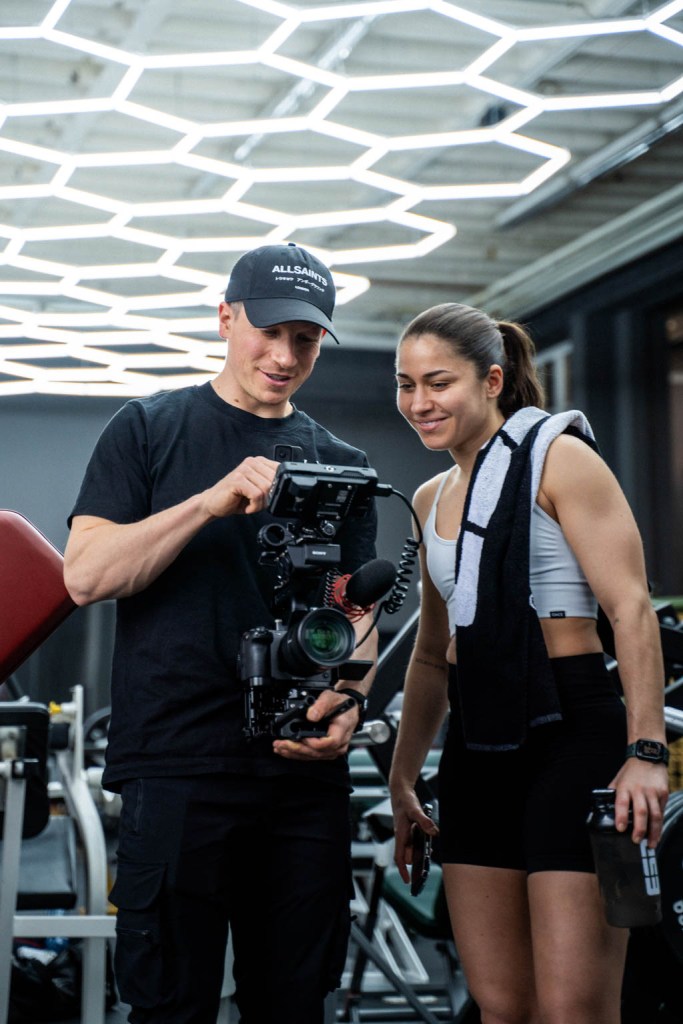 Behind-the-Scenes Foto aus einer Produktion bei einem Kunden. Zu sehen ist der Kunde (rechts) und Inhaber von Damm Media (links) nebeneinander im Sportstudio, während sie sich das Ergebnis des Shootings auf der Kamera ansehen.