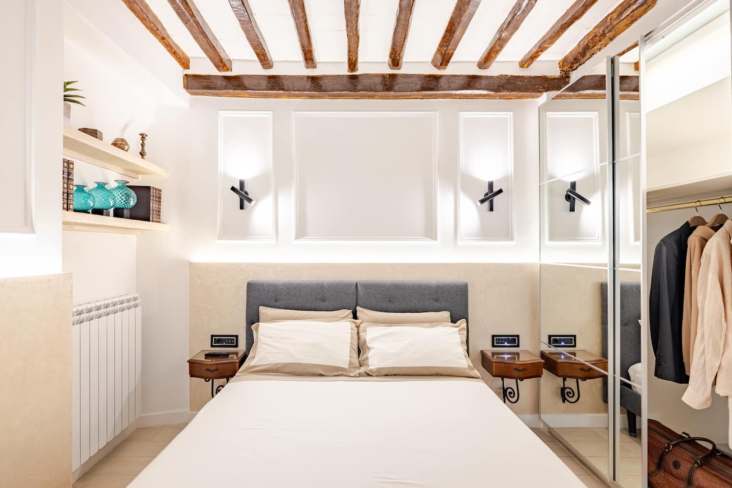A beautiful traditional-style bedroom with paintings on the walls, a carpeted floor, and a chandelier overhead.