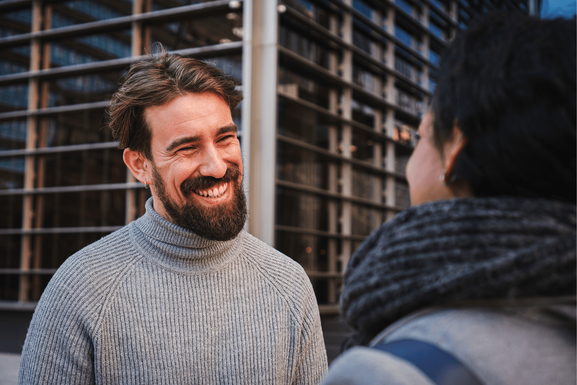 Close-up of two diverse marketing professionals in business attire smiling and discussing AI-driven strategy outside a modern office building.