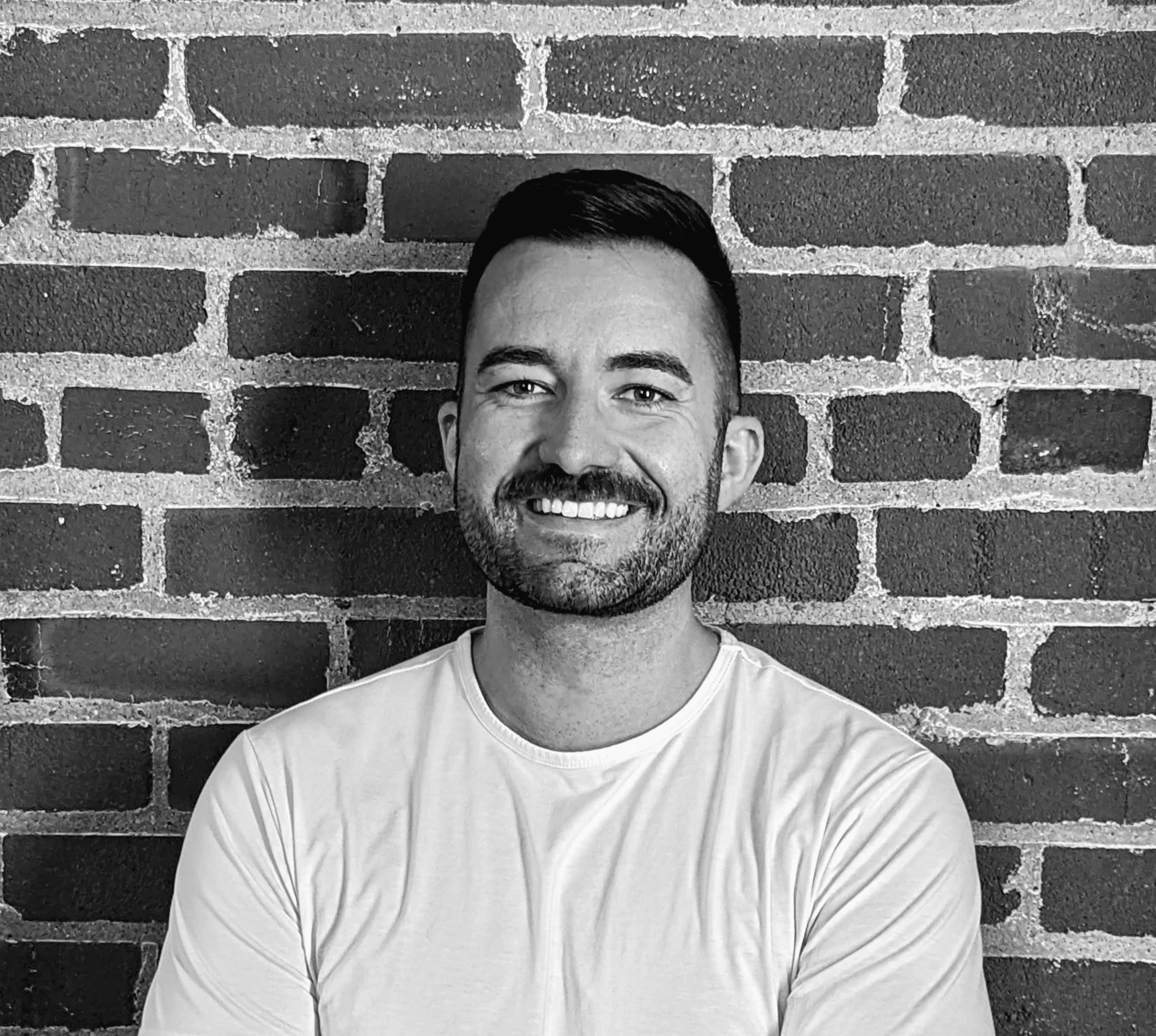 Black and white image of people working at a table with laptops, showing hands gesturing during discussion of digital content displayed on screens, with fabrica® logo in the corner.
