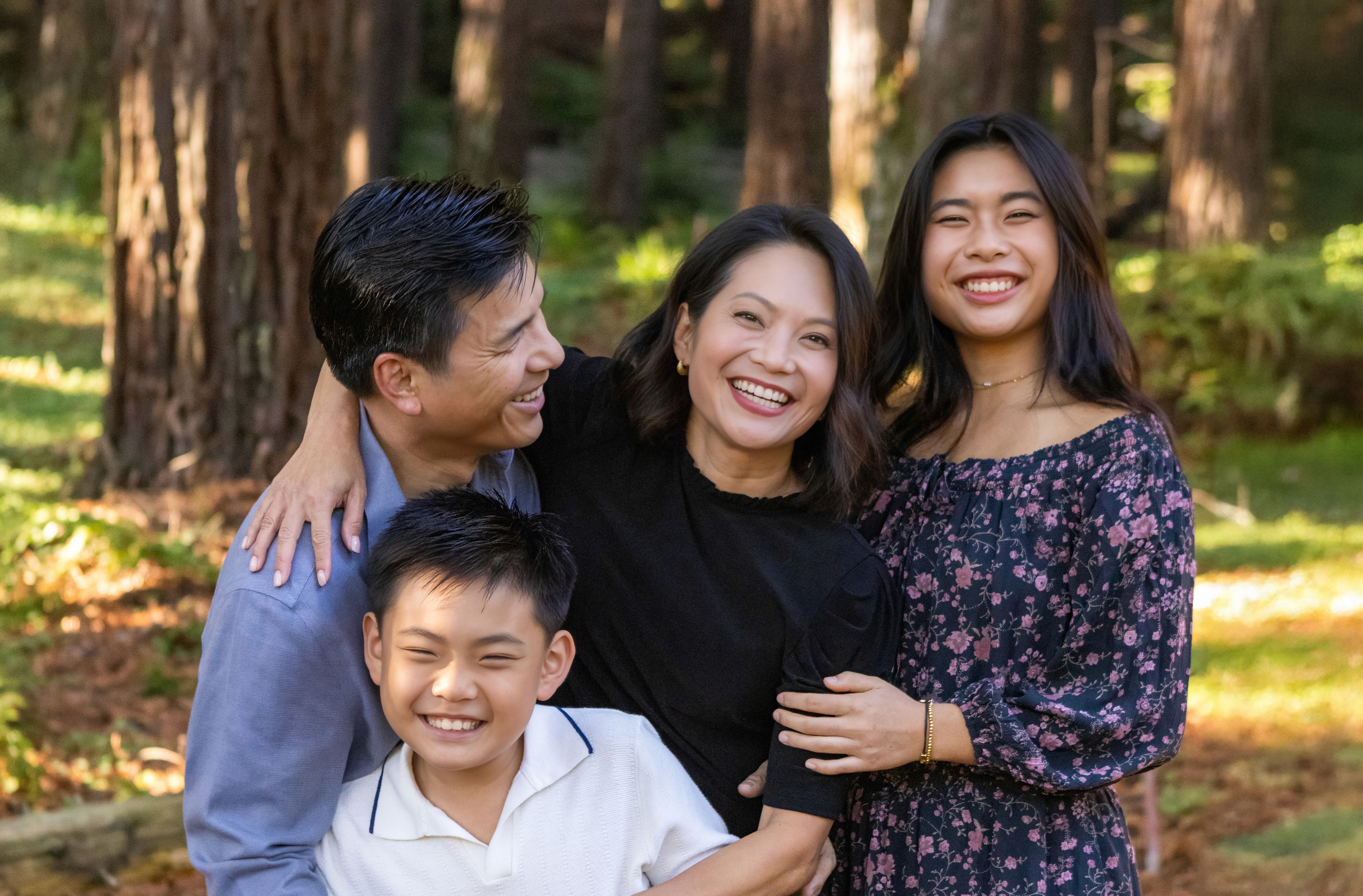 Family of four smiling together during an outdoor family photo session before senior year