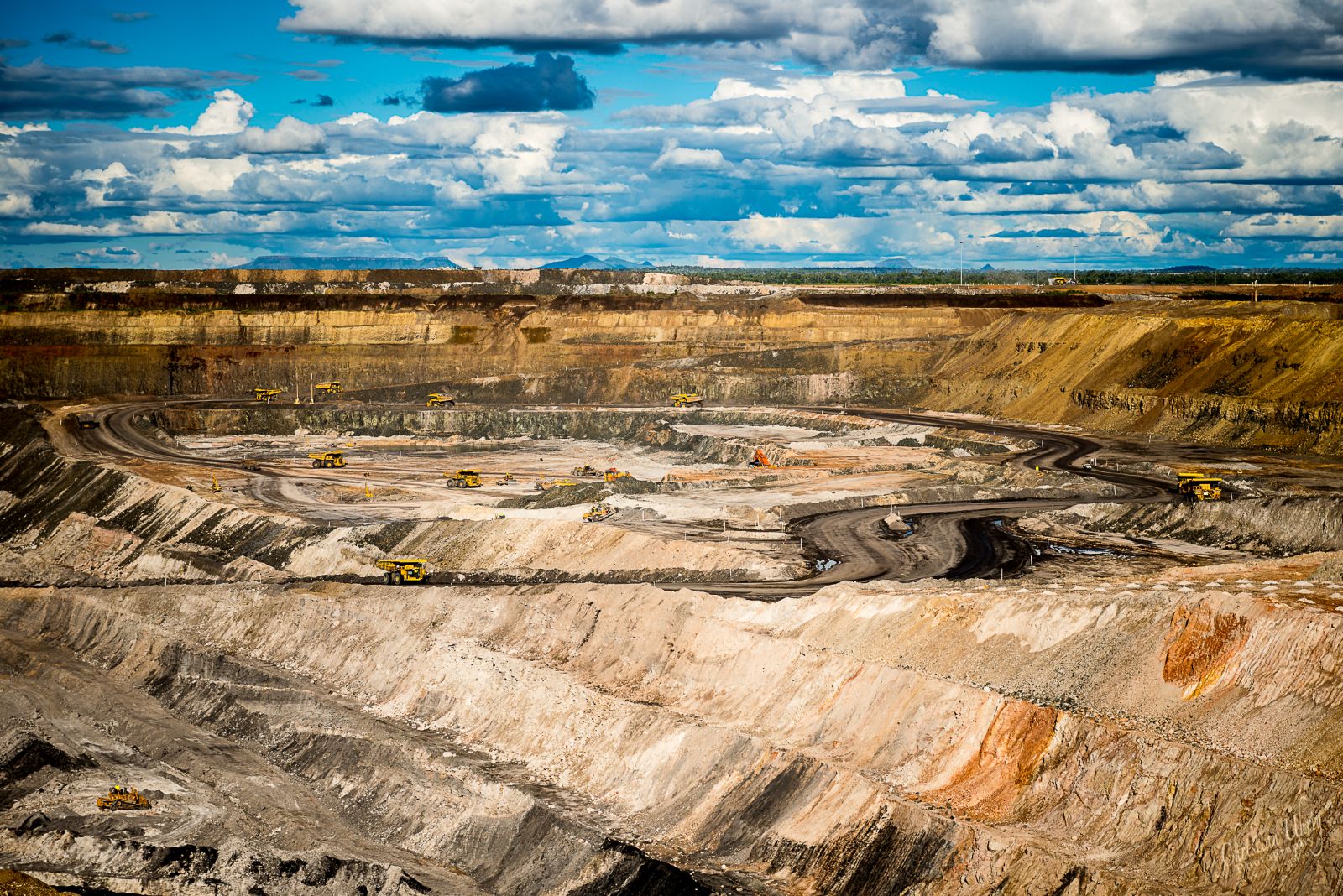 UMINEX sustaining capital infrastructure project showing an aerial view of a large open-cut mining operation with terraced excavation, haul roads, and active heavy mining equipment