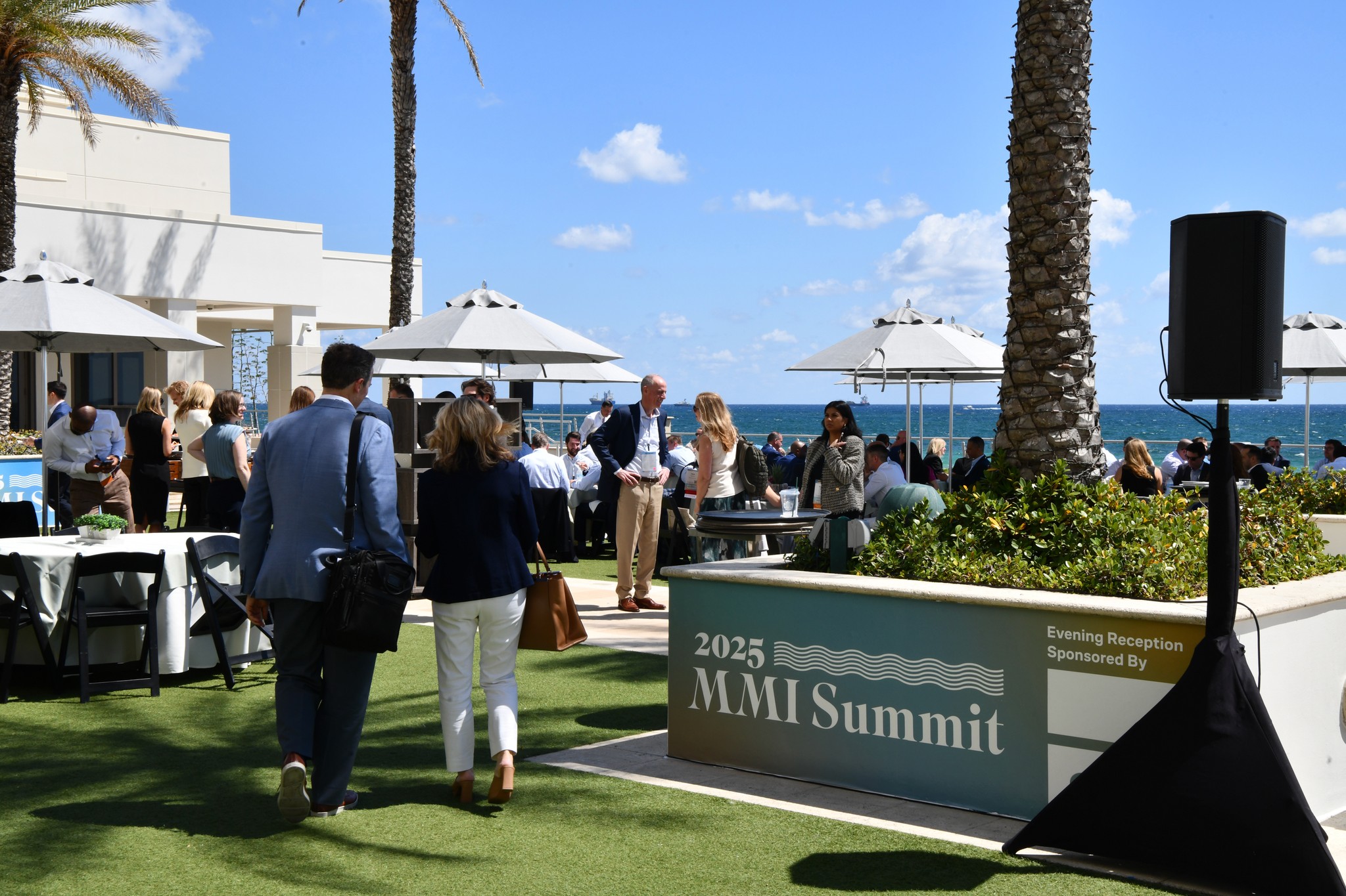 2025 MMI Summit outside of the hotel overlooking the beach on a sunny day with MMI Summit branding on a vinyl cling on a planter in the foreground on the right