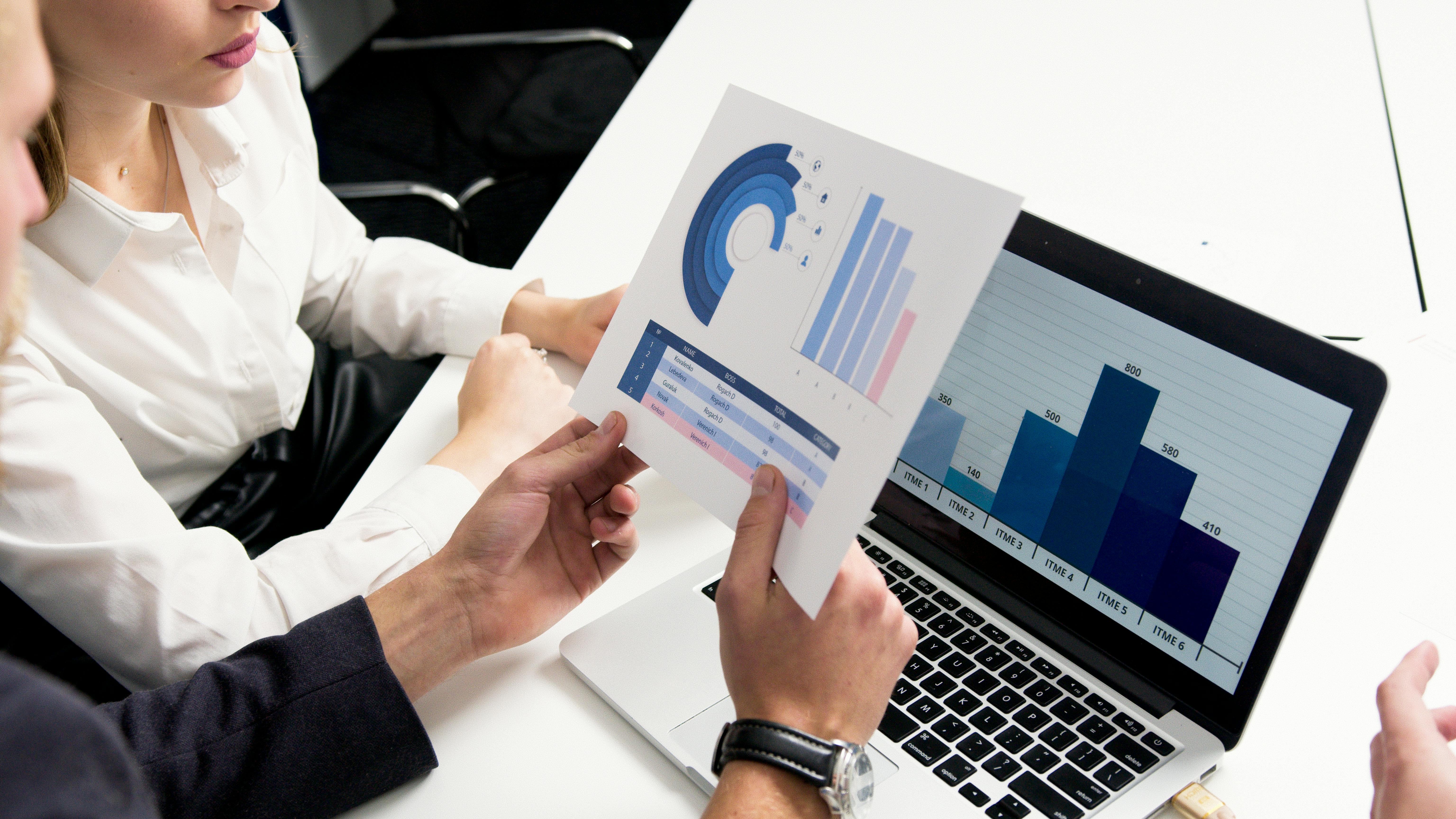 A group of business individuals reviewing data graphs on a laptop screen