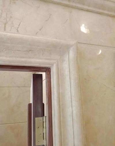 A close-up of marble trim surrounding a doorway, showcasing intricate detailing and smooth finishing. The marble frame adds elegance and refinement to the entrance.