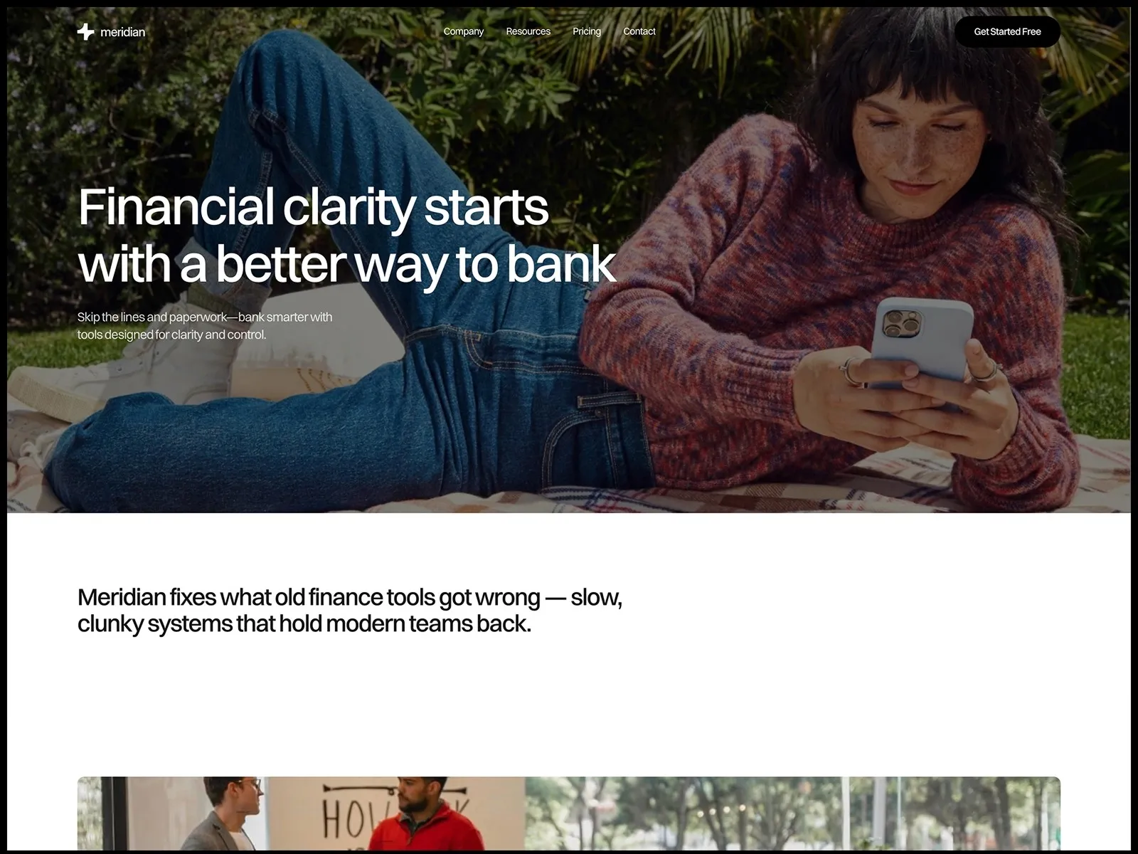 Woman in casual attire using phone outdoors, surrounded by lush greenery.