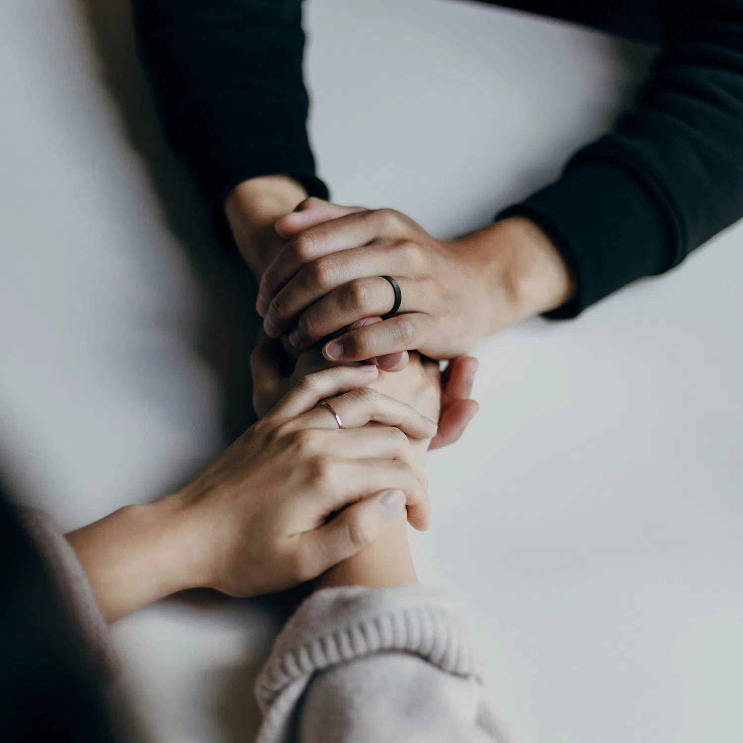 Close-up of two people holding hands in a supportive gesture during an LGBTQ codependency therapy session in Los Angeles, focusing on healing and healthy relationships.