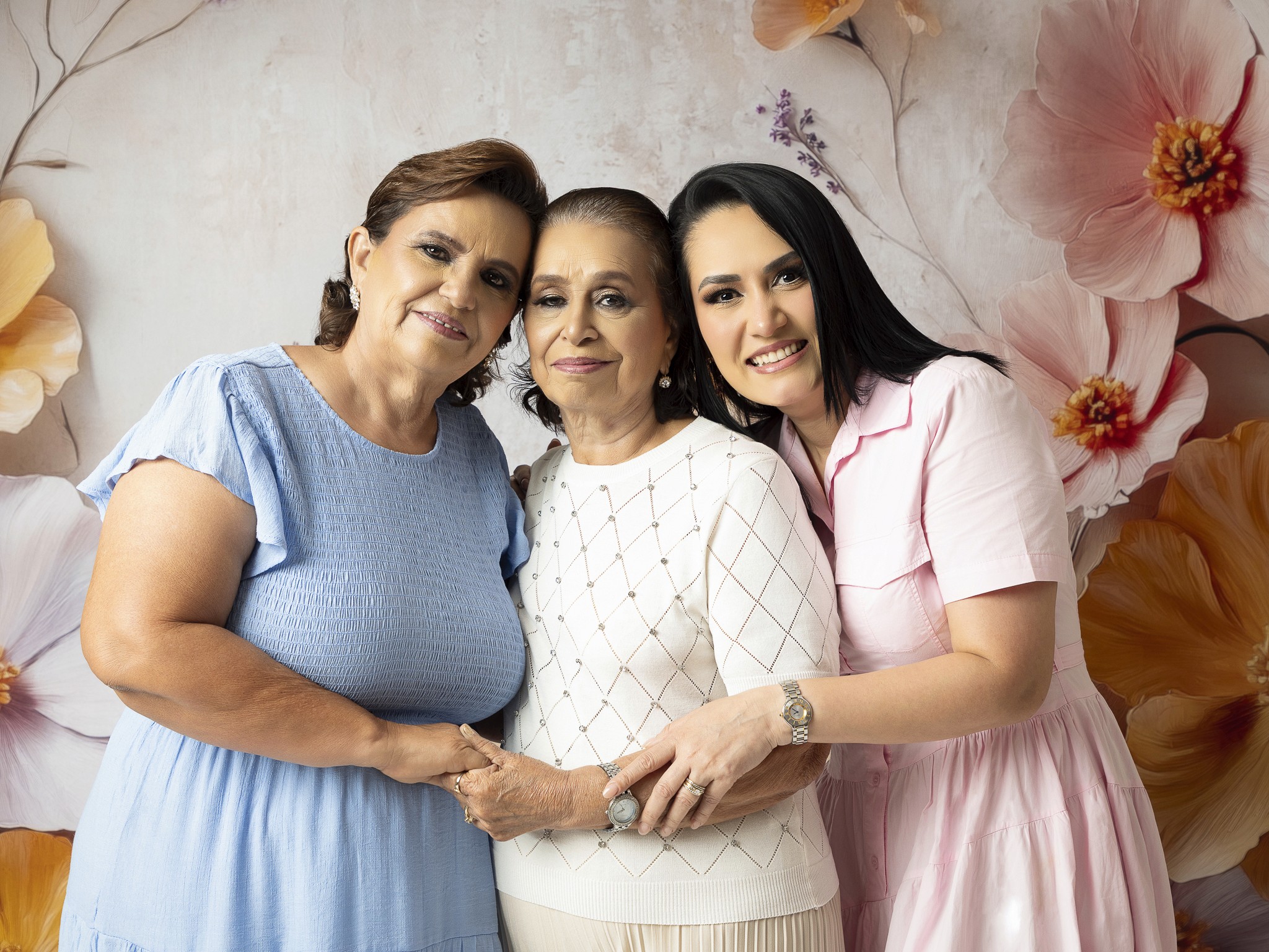 retrato de tres generaciones familiares sonriendo juntas en estudio fotográfico