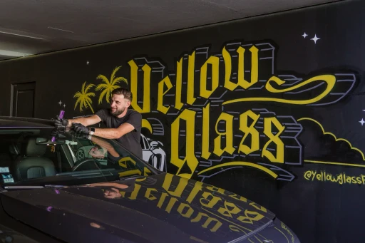 Deux hommes devant un camion jaune, l'un montre quelque chose à un autre, souriant, avec le logo de l'entreprise.