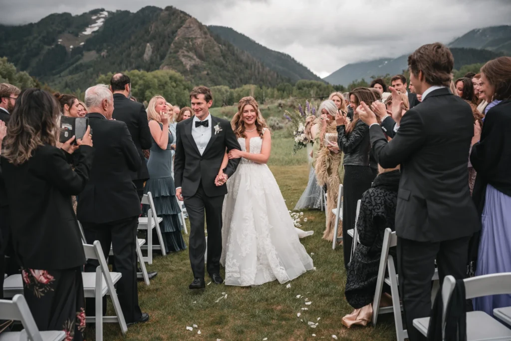 Newlyweds walking up the aisle while guests applaud