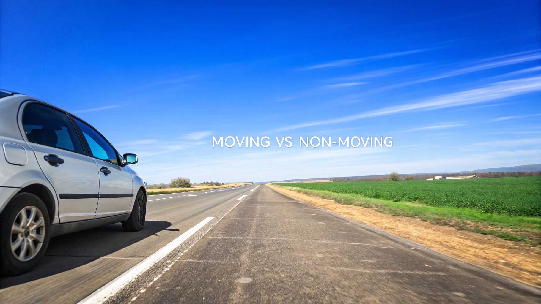 A silver car parked on a long, open road, with green fields and a blue sky, showcasing moving vs non-moving.
