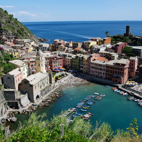 一座海滨小镇，拥有色彩缤纷的建筑、一座教堂，以及停泊在小港口中的众多船只，四周环绕着群山与大海。