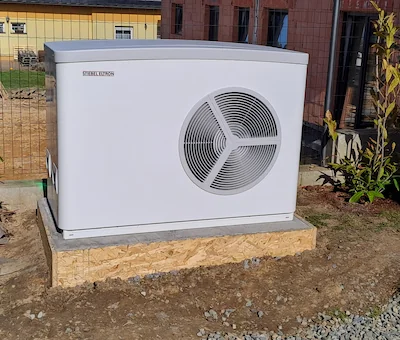 Venkovní jednotka tepelného čerpadla Stiebel Eltron na betonovém základu u novostavby.