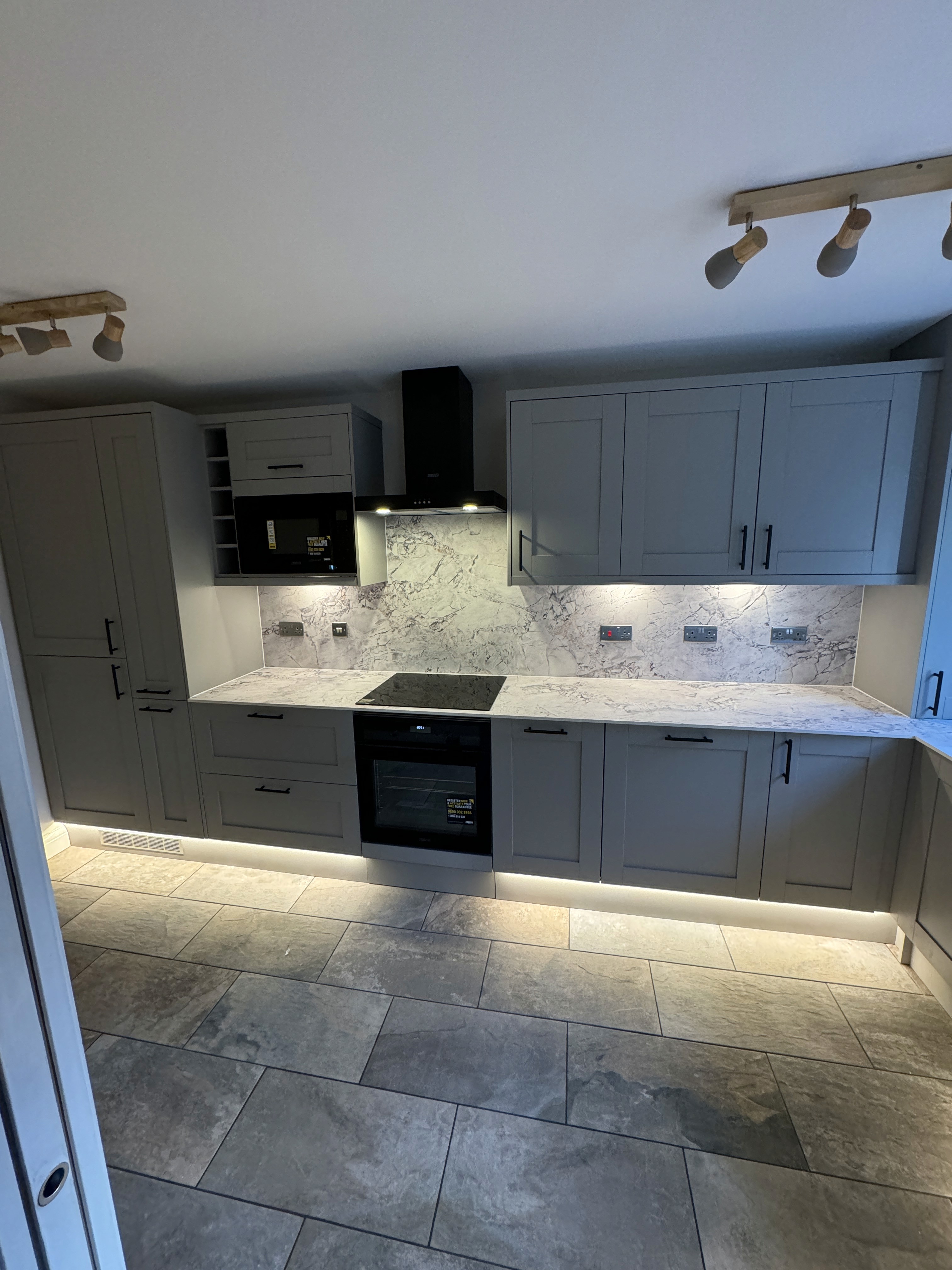 Modern kitchen with a wooden dining table, white chairs, and a hanging light fixture above.