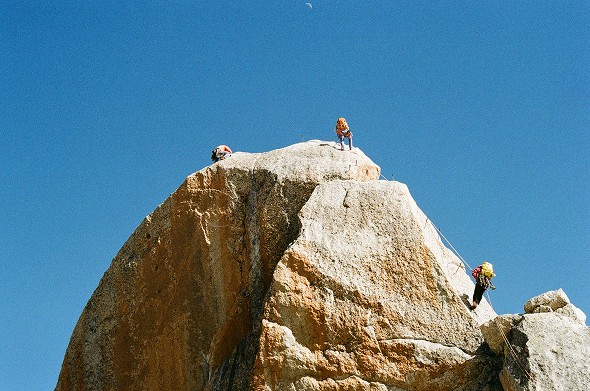 Klettern an einer großen Felswand unter blauem Himmel – Fokus auf Technik, Teamwork und Outdoor-Klettererlebnis als Inspiration fürs Bouldern.