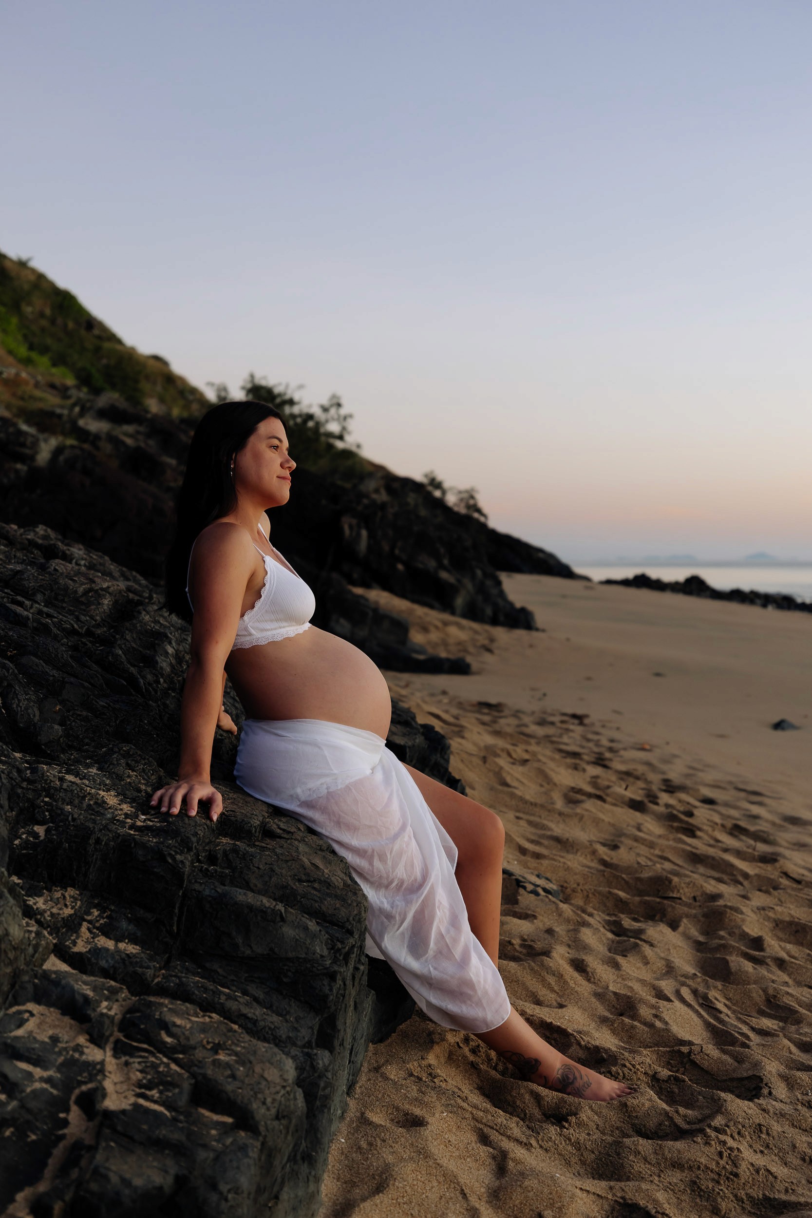 Mackay maternity photography Blacks Beach woman on sandy beach with rocky backdrop at sunrise