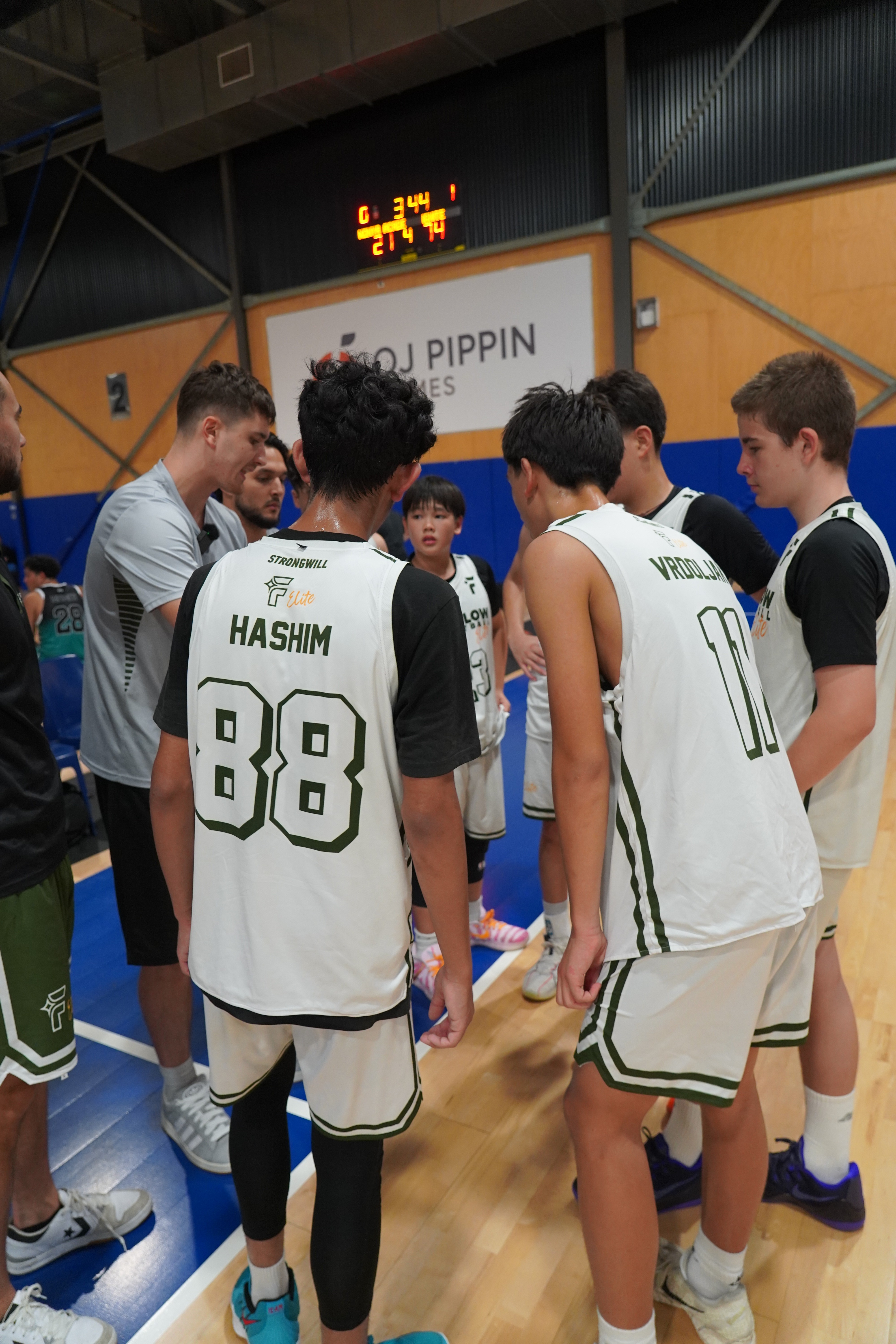 Free Flow Basketball players in a huddle listening to Coach Jorgos