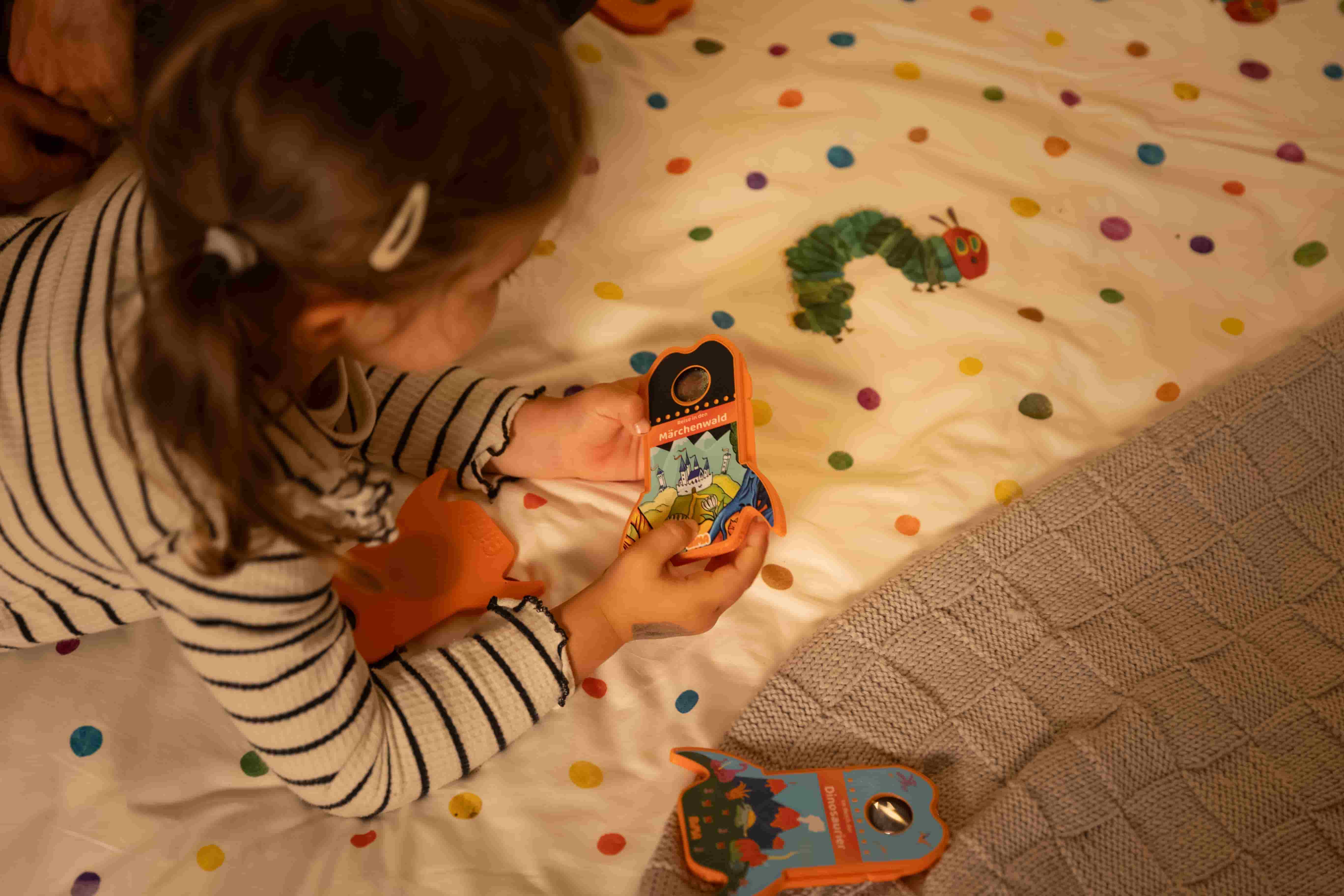 Ein Kind liegt auf dem Bett und schaut sich die BiMA Raketen an