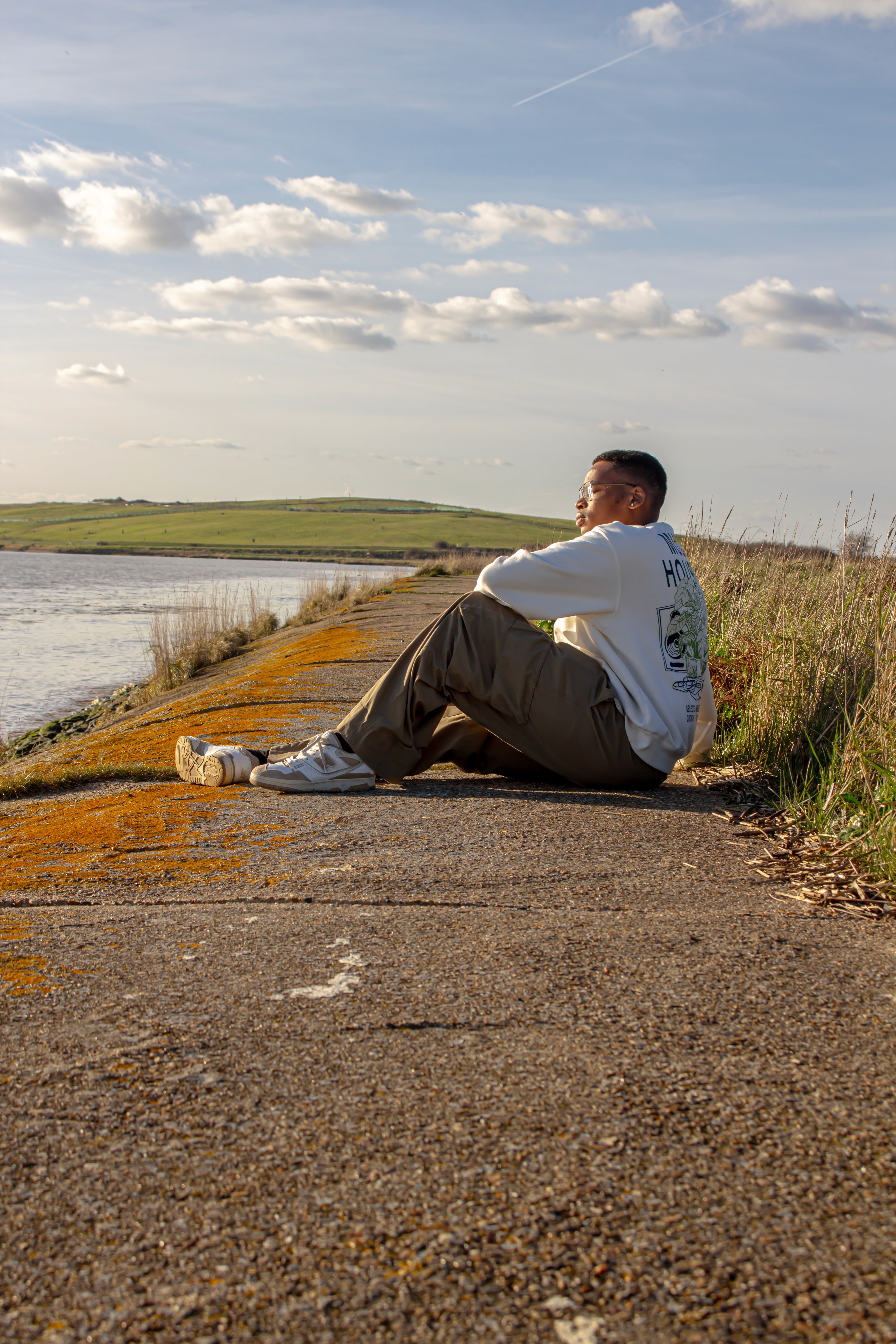 Tyrone grounded in nature, sitting near water with lush plants around them.